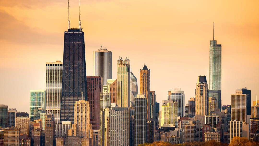 View of the Chicago skyline basked in a golden glow. The John Hancock Center tower is featured. 