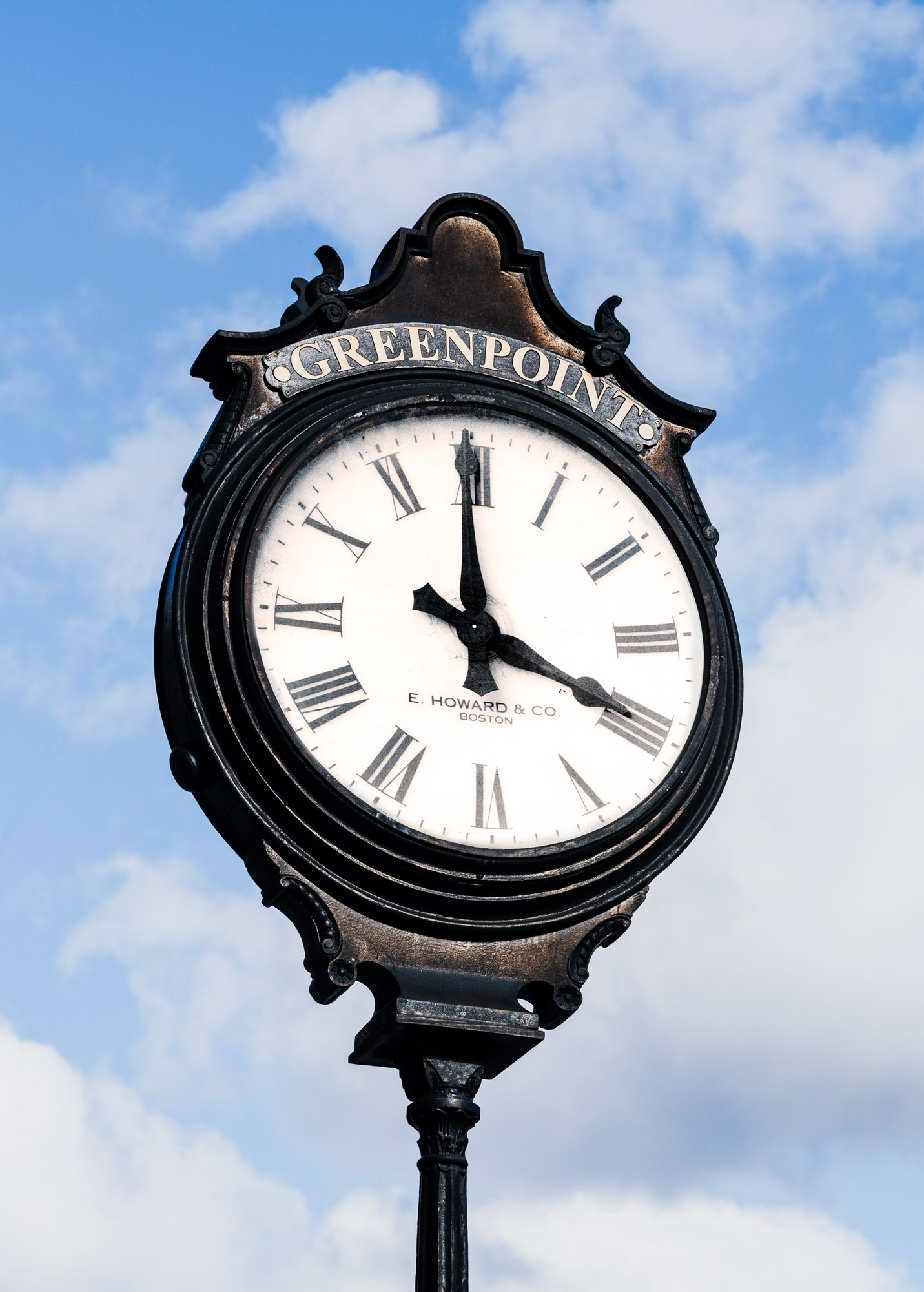 A clock with the word Greenpoint over it in Brooklyn, New York near Two Blue Slip apartments.