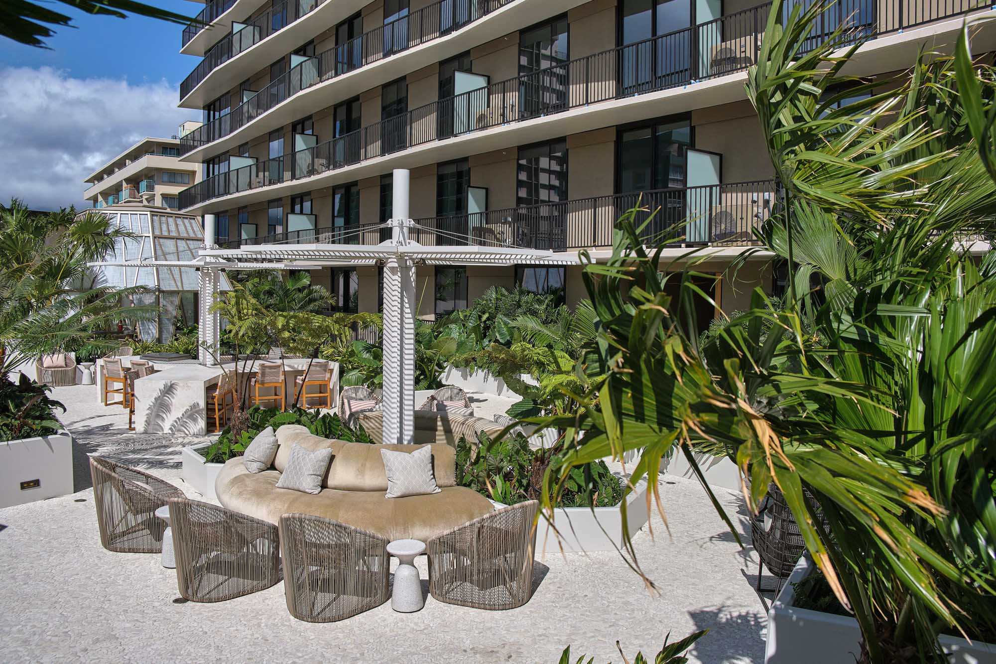 Terrace with plush seating areas, surrounded by palm trees.