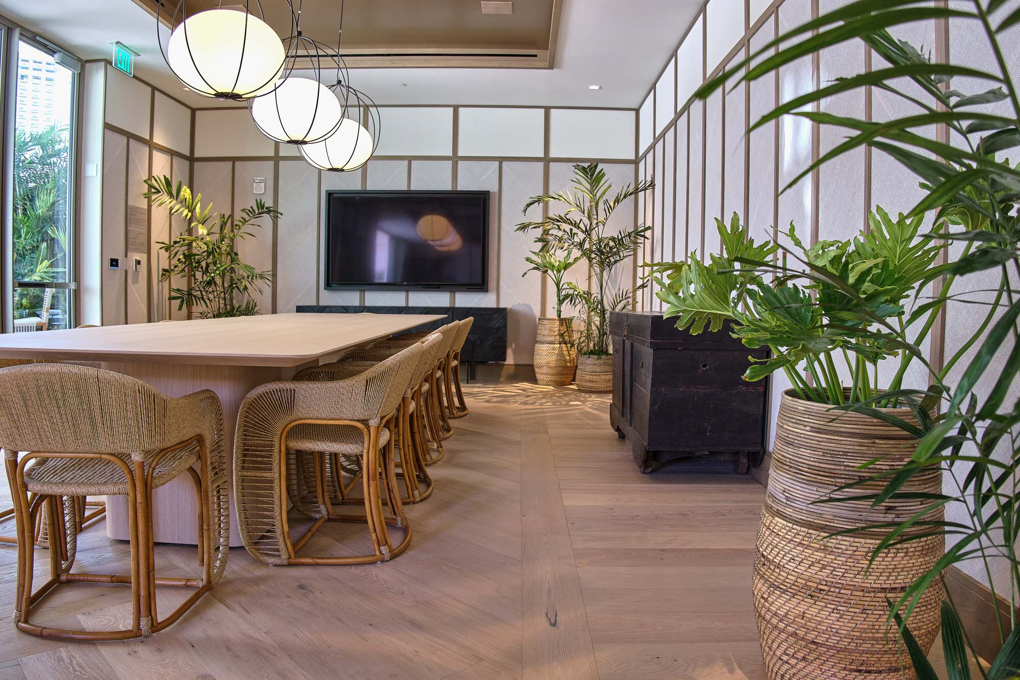 Conference room table with wicker chairs and television.