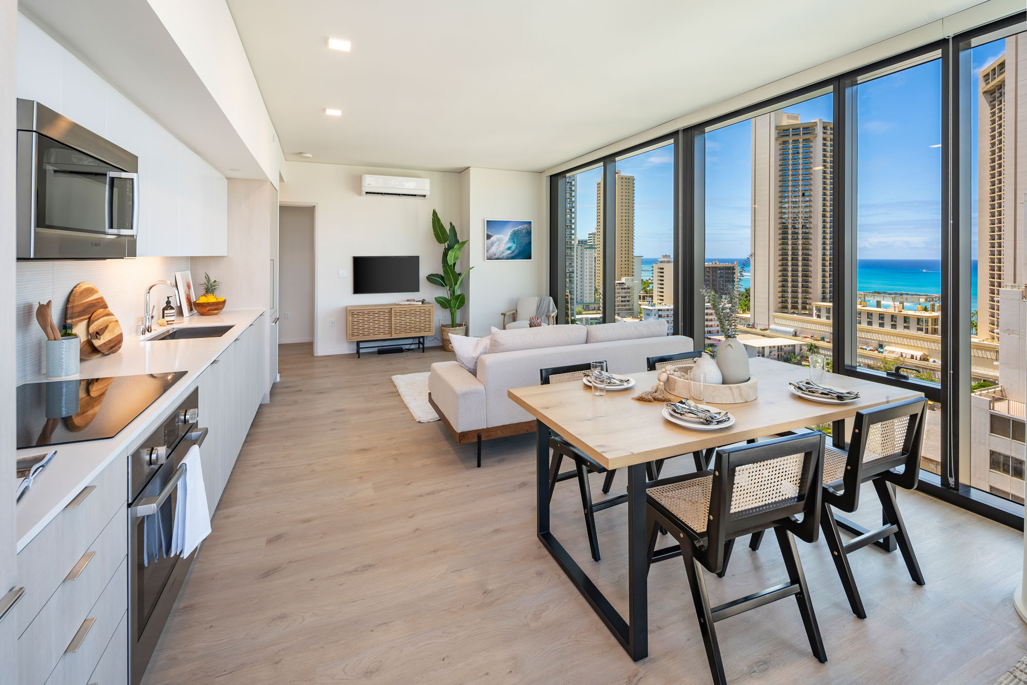 Open floor plan with dining and living area near floor-to-ceiling windows with a view of Waikiki Beach.