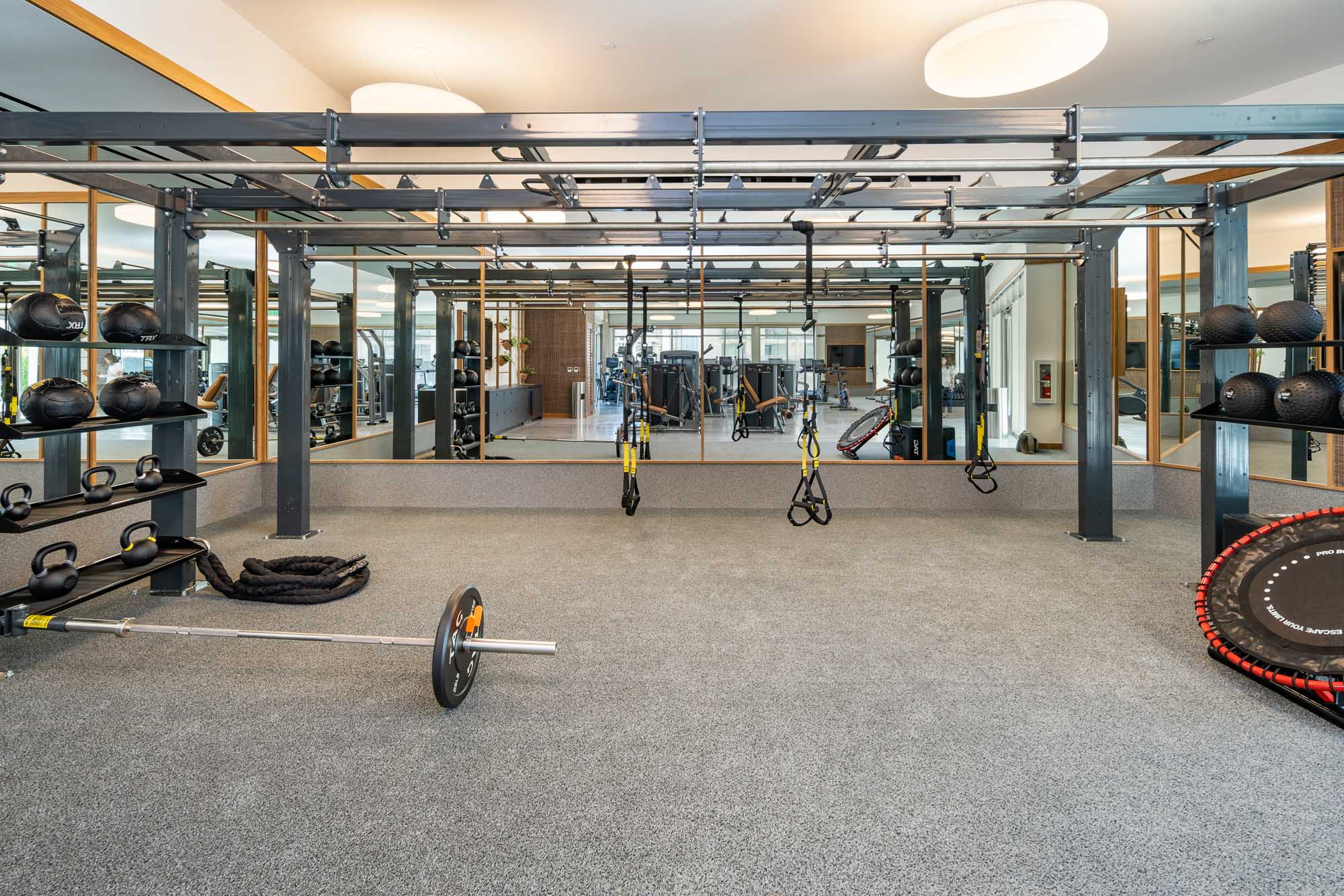 A fitness center with TRX bands and various weights.