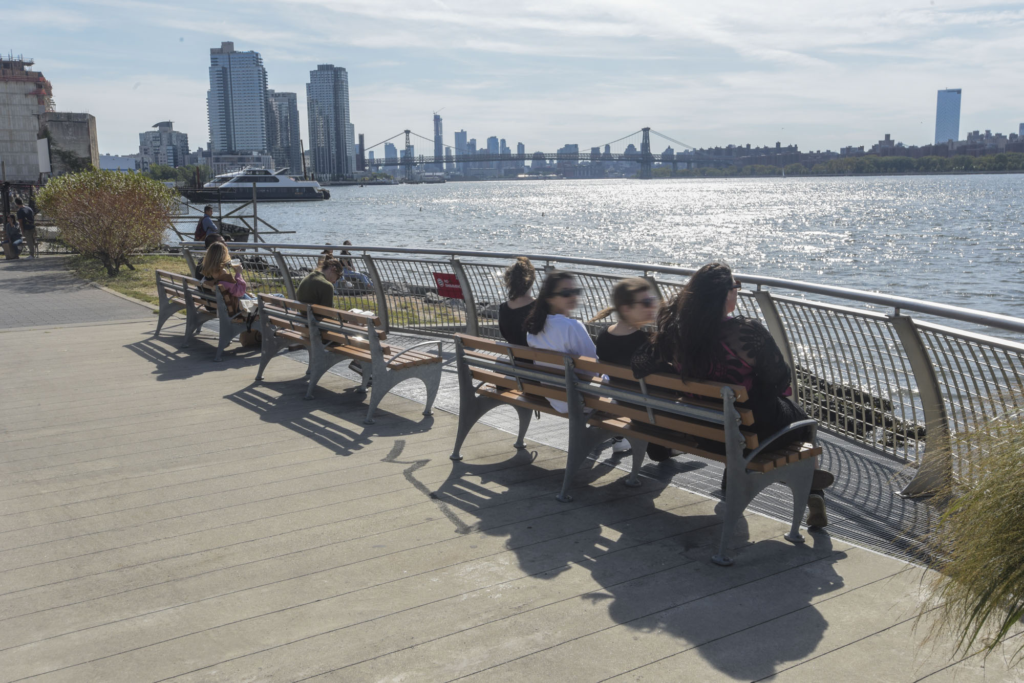 Three park benches sit adjacent the East River in Greenpoint Landing.