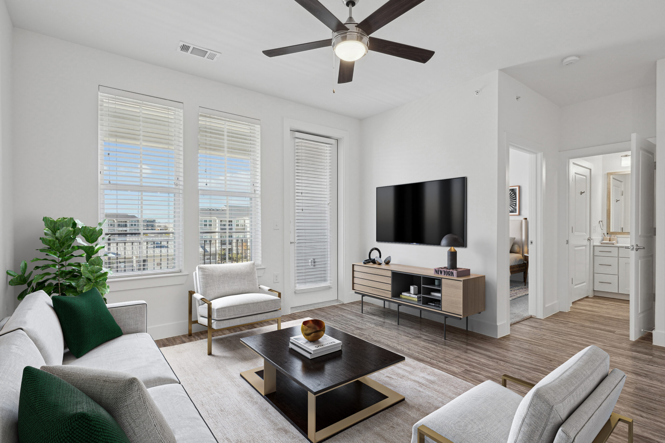 A Modern Garland, Texas apartment living room with large windows, wood-style floors, ceiling fan, and contemporary furniture in