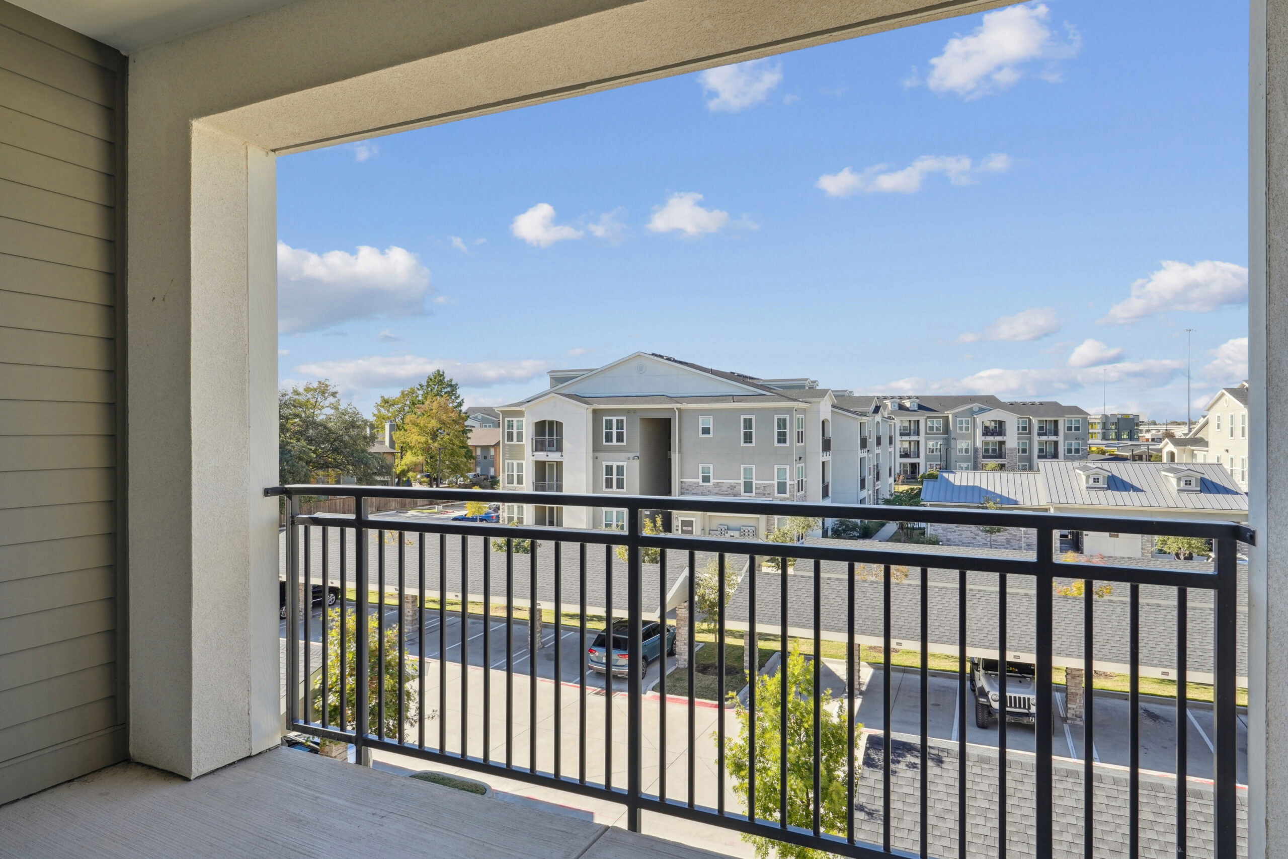 Balcony view from Garland TX apartment rentals overlooking modern residential buildings near Dallas at Embree Hill