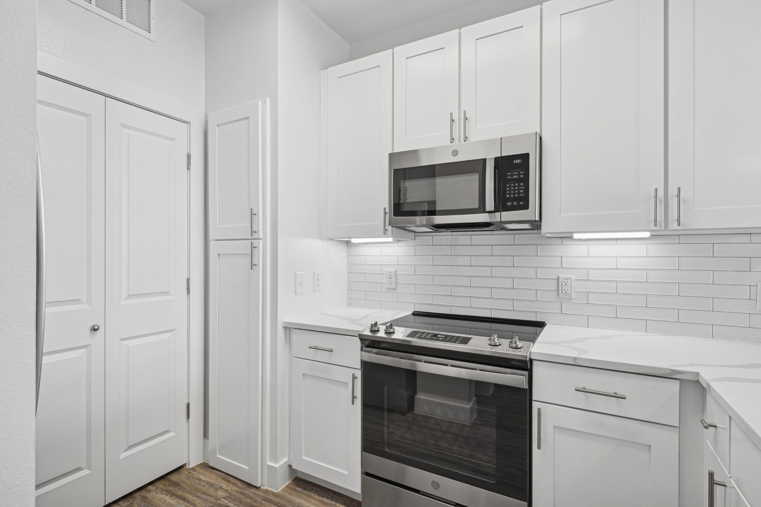 Modern, all white kitchen with marble counters, contemporary finishes finishes and stainless steel appliences in a Garland Texas apartment