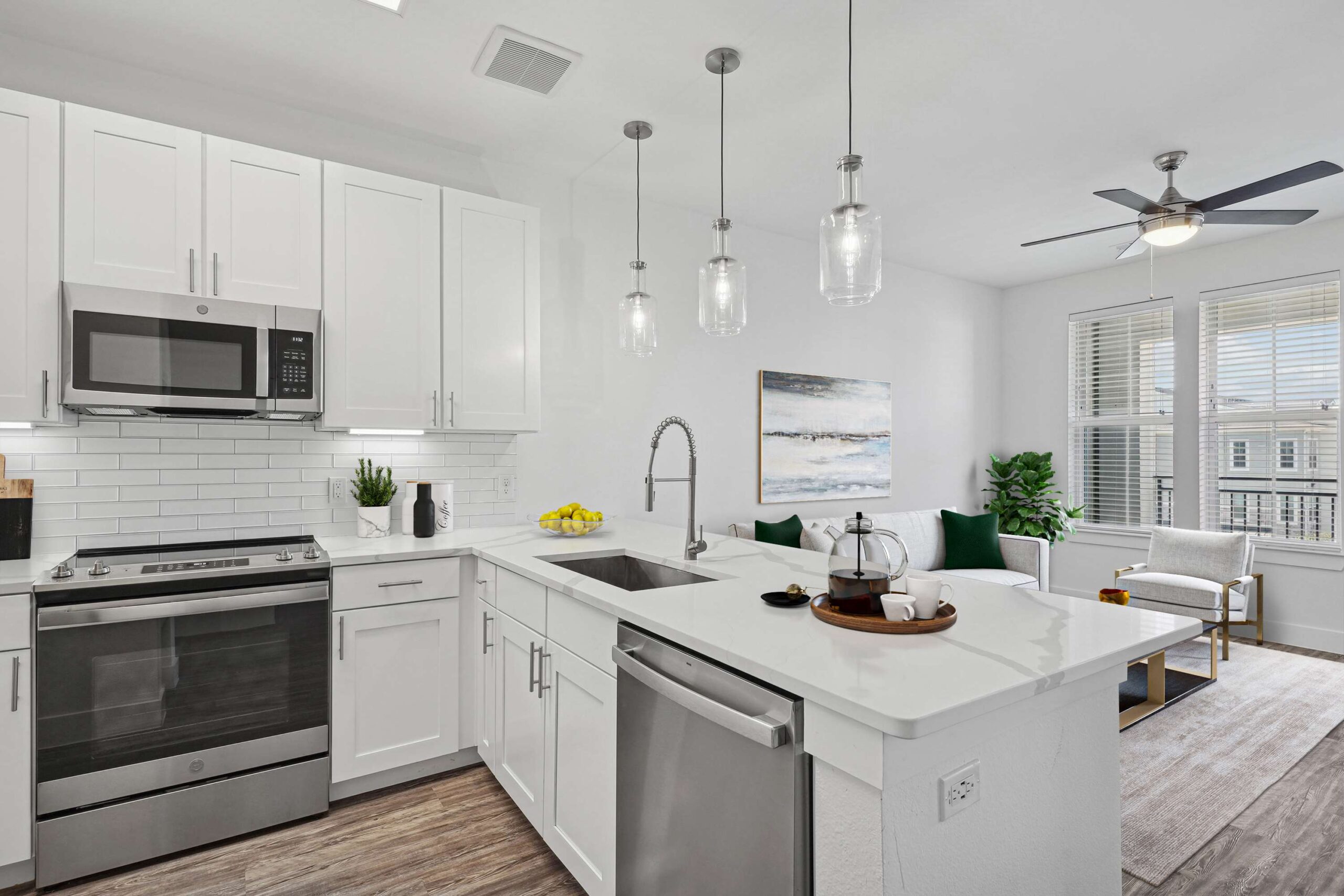 Modern kitchen with stainless steel appliances and white marble countertops in apartments in Garland Texas, overlooking a bright open-concept living area
