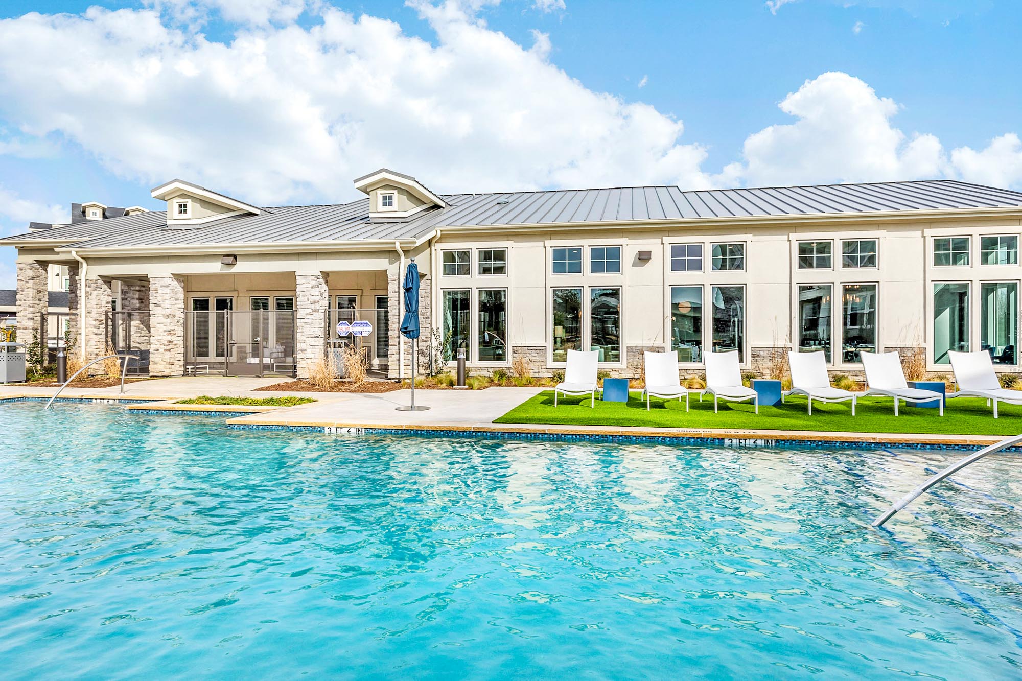 The exterior of an apartment building with a pool at Embree Hill in Dallas, TX.