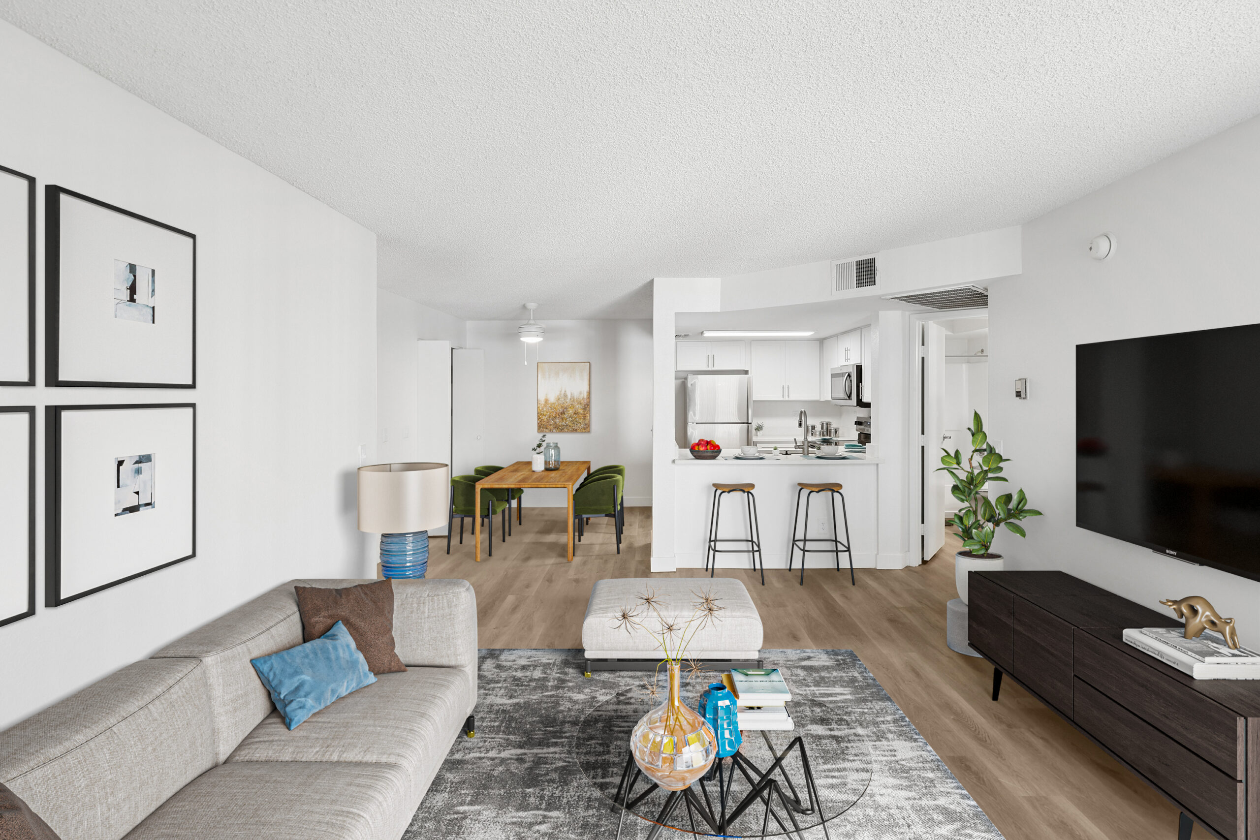 Open-concept living and dining area at Meadow Glen featuring wood-style flooring, a breakfast bar, and a bright kitchen with white cabinetry and stainless steel appliances.