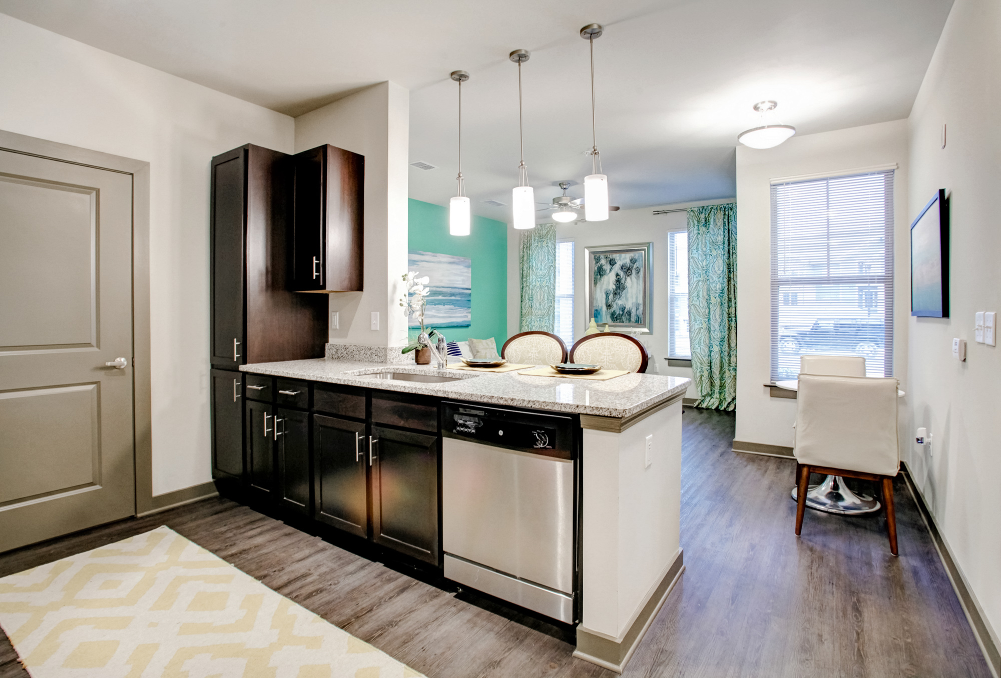 A galley-style kitchen opens to a living room with mint green walls and beautiful window treatments.