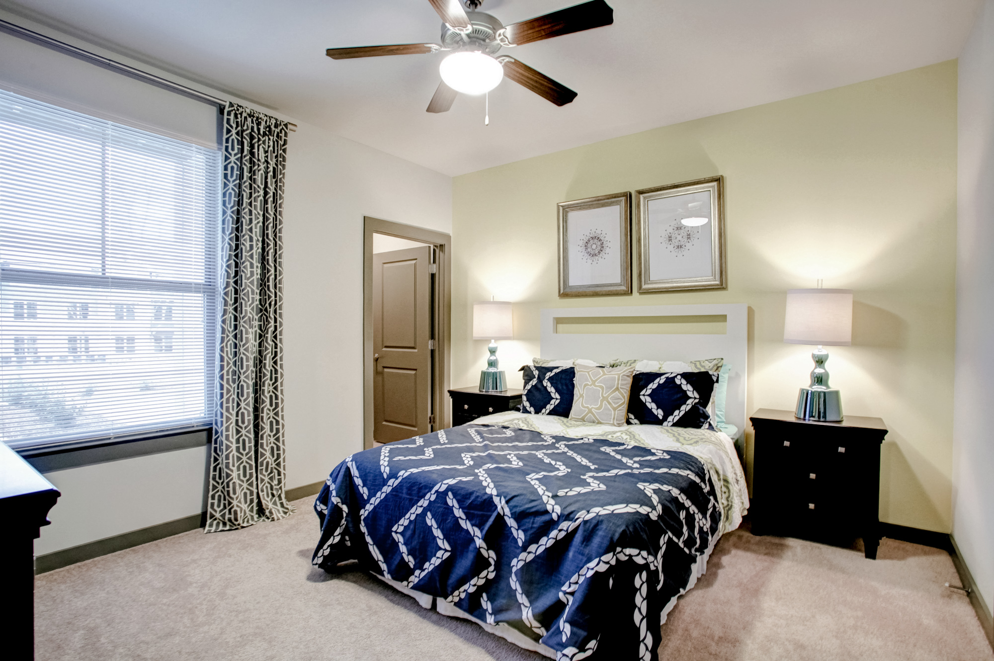 A bed with blue bedding sits against a yellow wall.