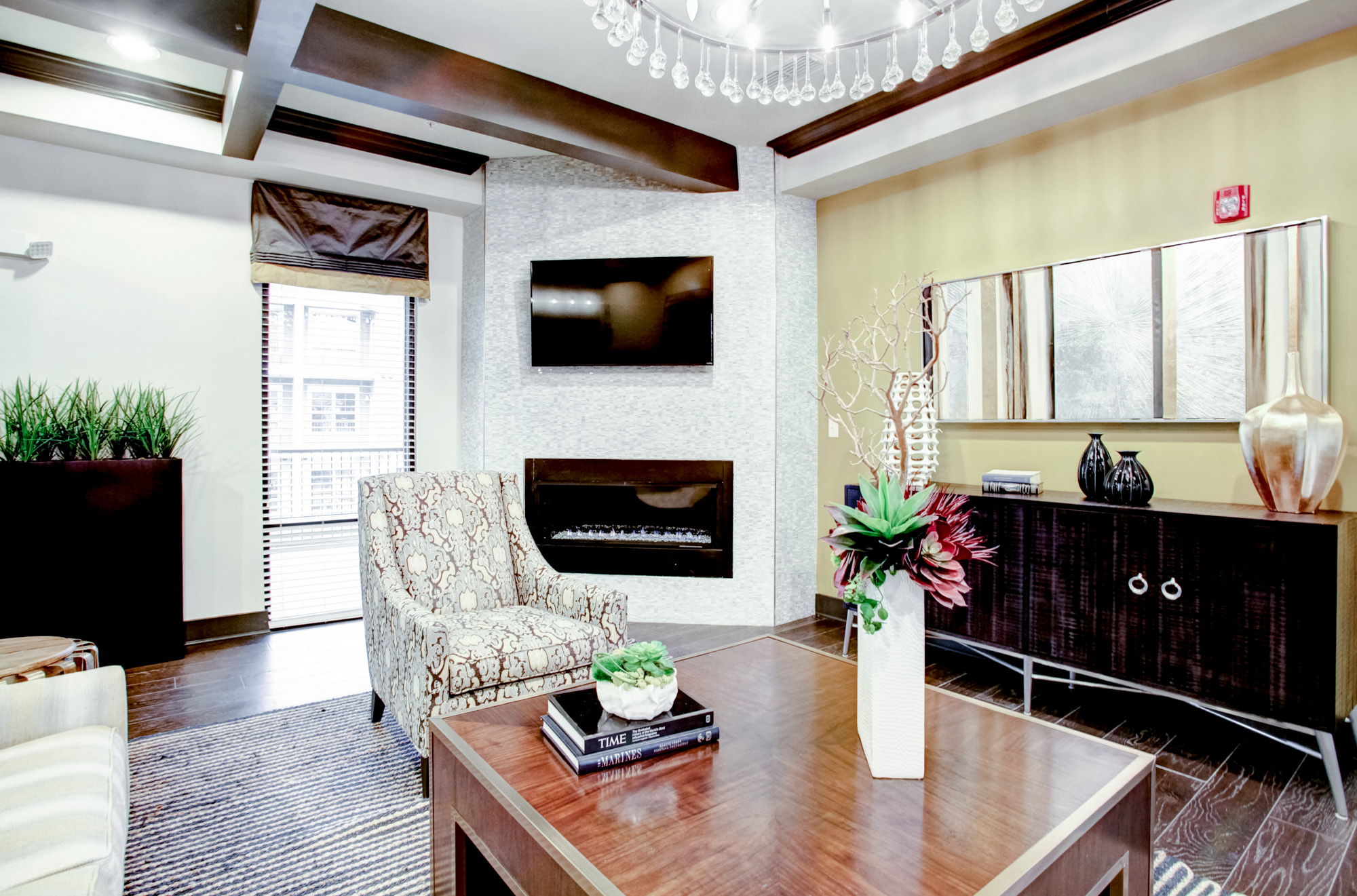 A seating area and console are in the foreground with a fireplace and flat screen television overhead.