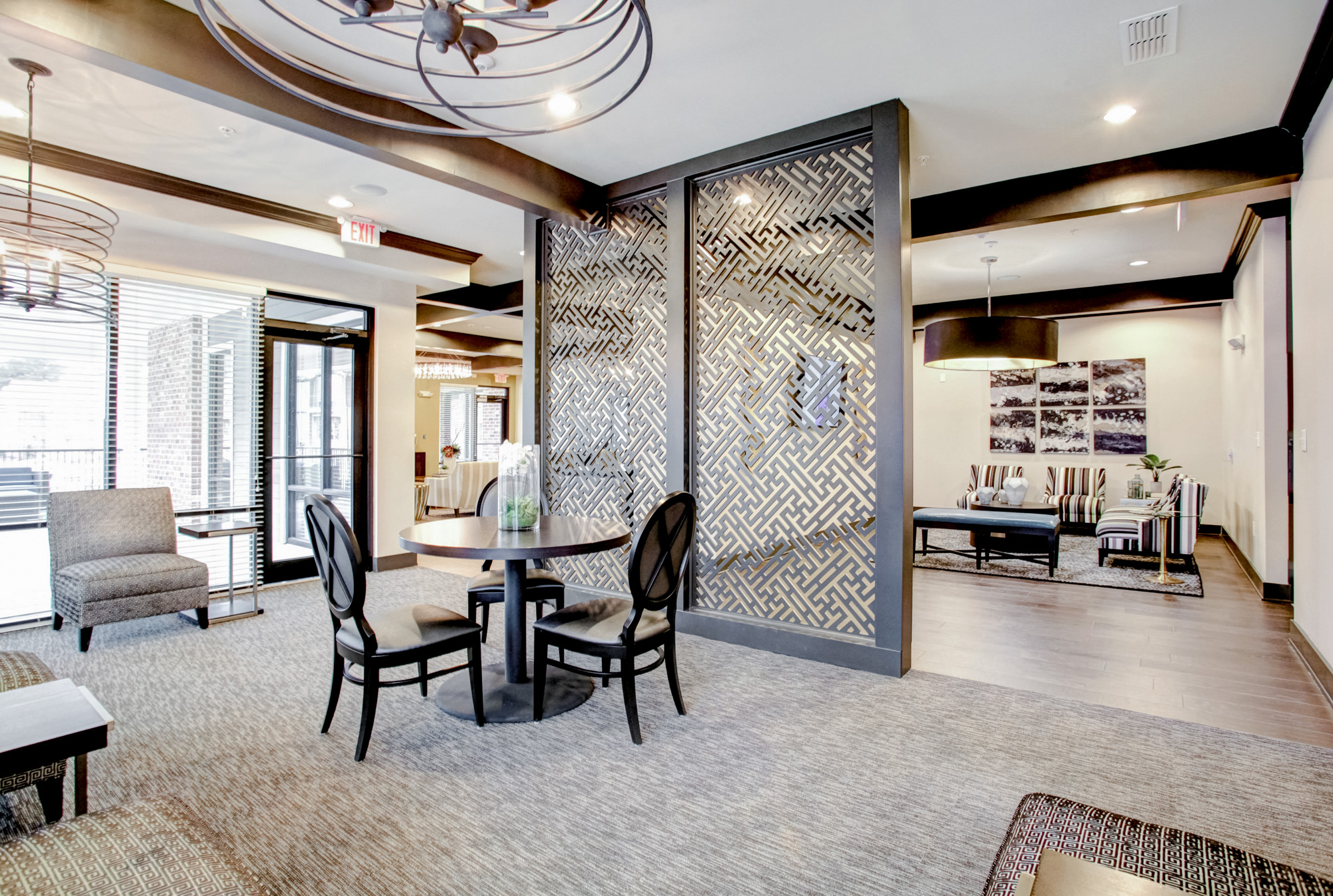 A table surrounded by three chairs sits in the foreground with a partition wall separating it from an adjoining room.