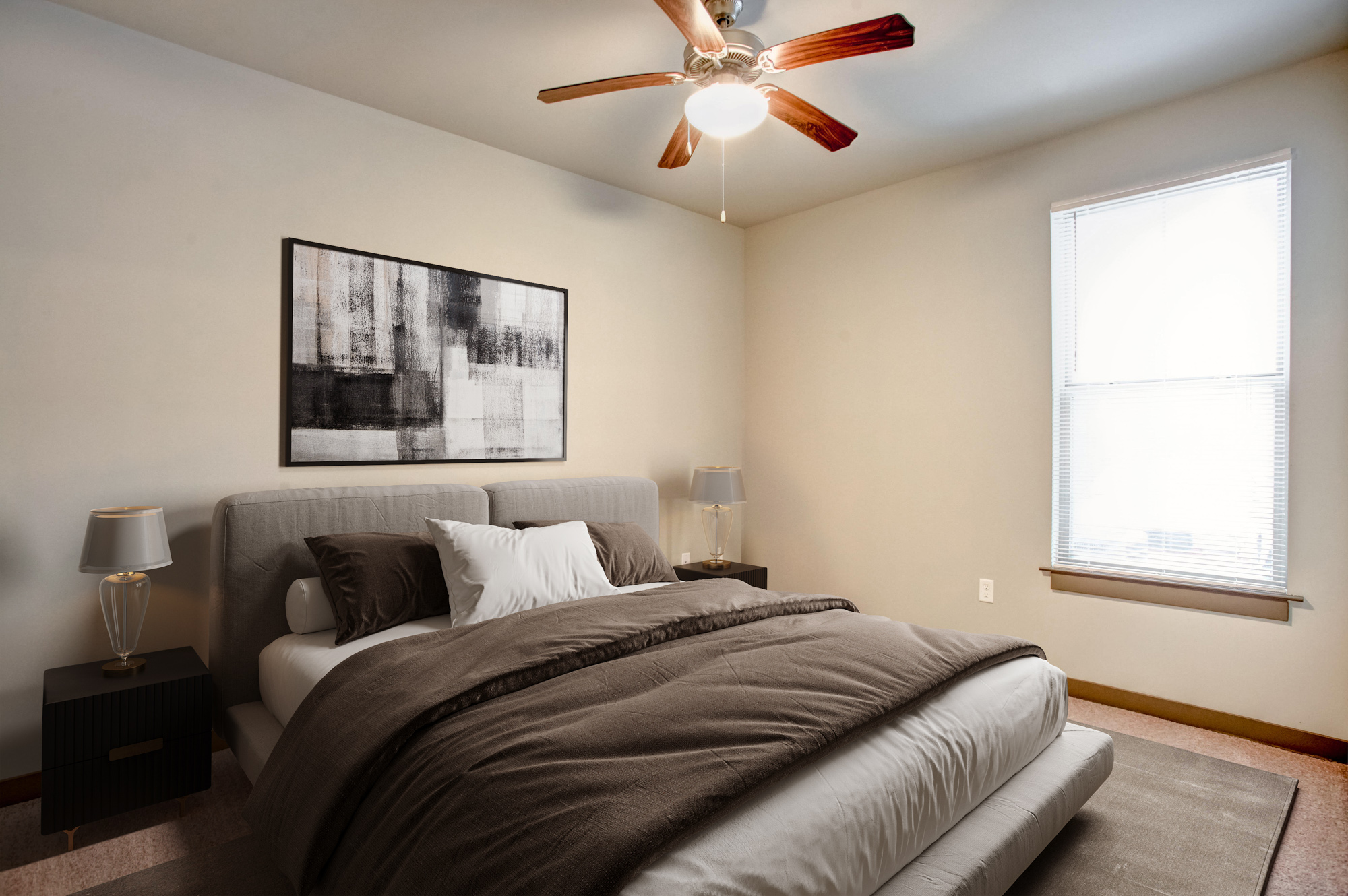 A bed with brown bedding sits in a room with a picture window at Park 9 apartments.