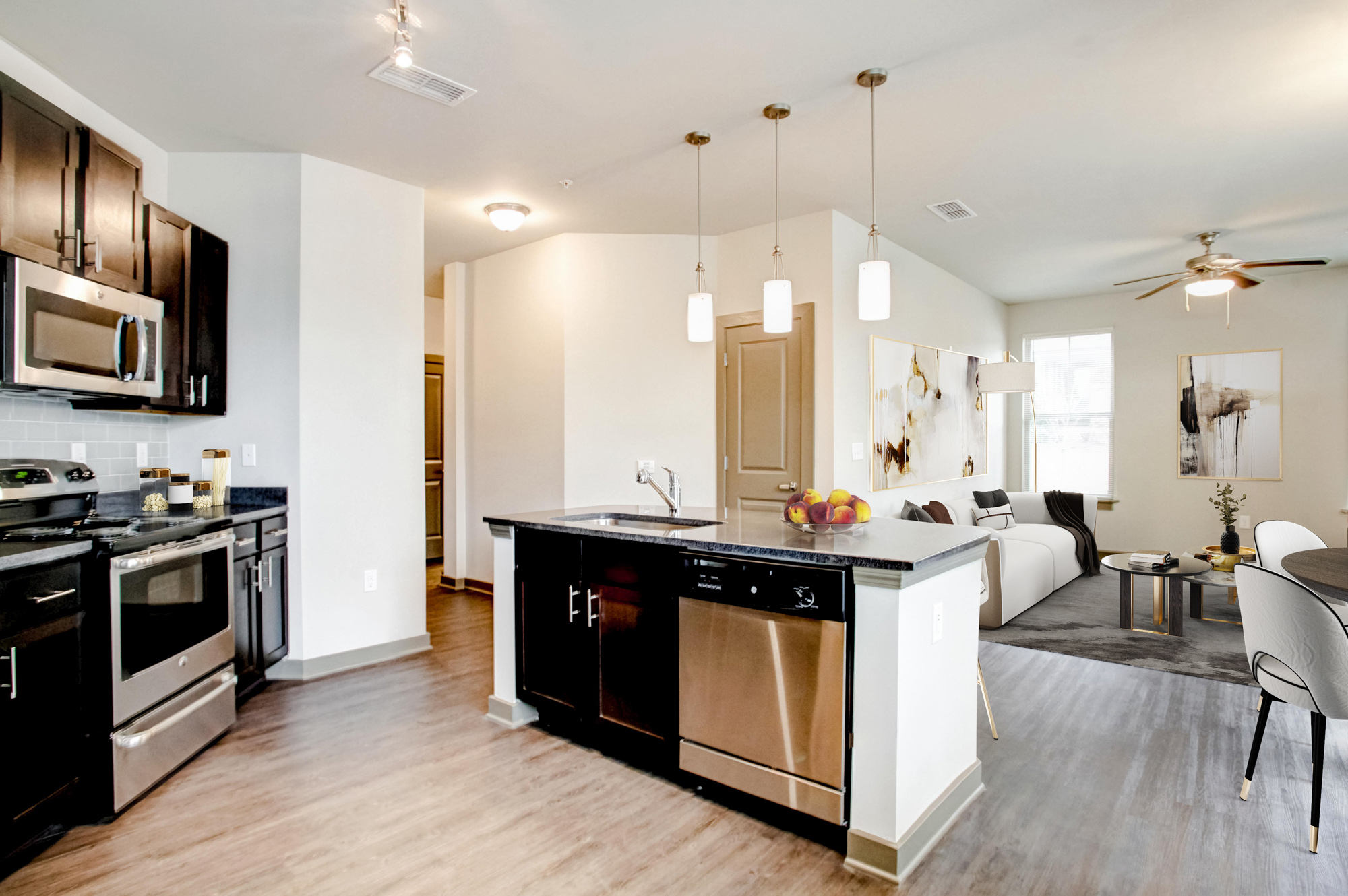 A kitchen with stainless steel appliances is on the right with a living area on the left.