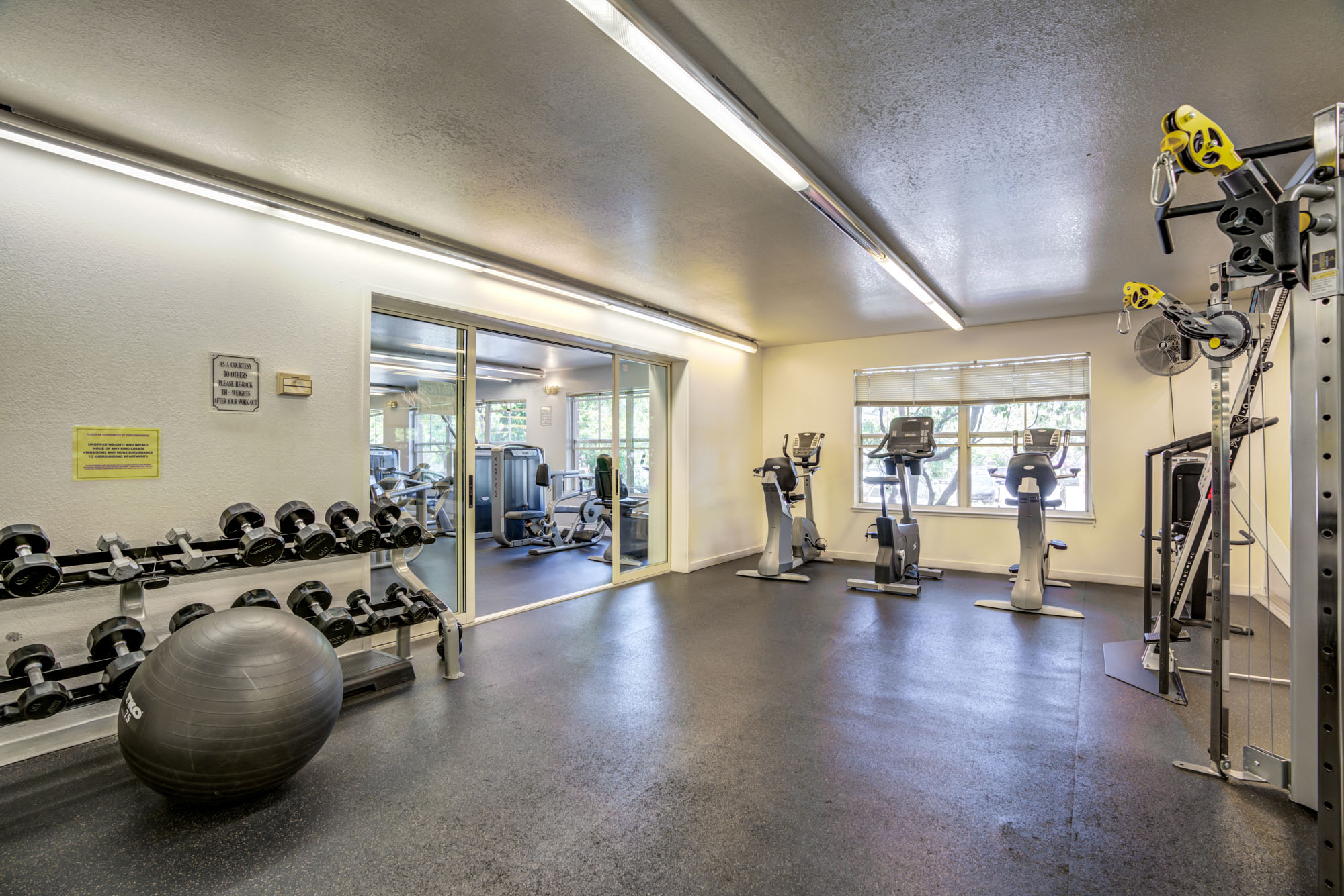 A fitness center with weights, fitness balls, stationary bikes and cable machines in a private section at Bayside Villages modern apartments in San Francisco