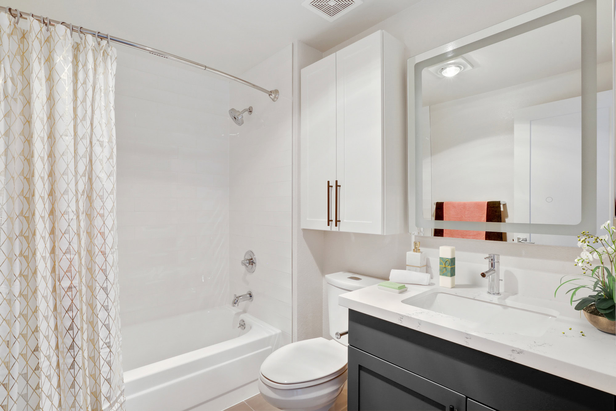 A bathroom with white and gray cabinets and a large vanity mirror at Bayside Village apartments in San Francisco