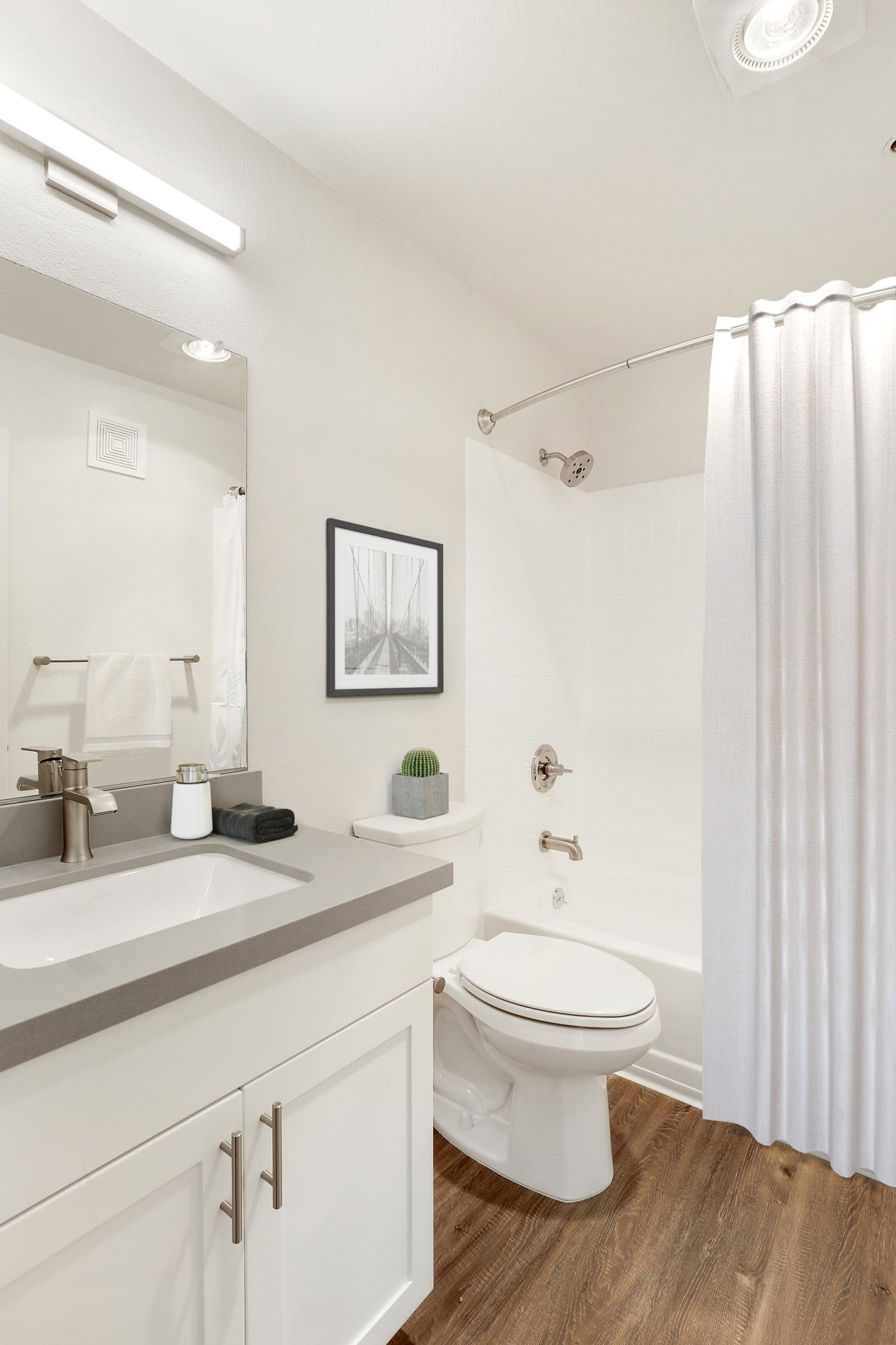 A bathroom with hardwood floors and white cabinets in a Bayside Village apartment in downtown San Francisco