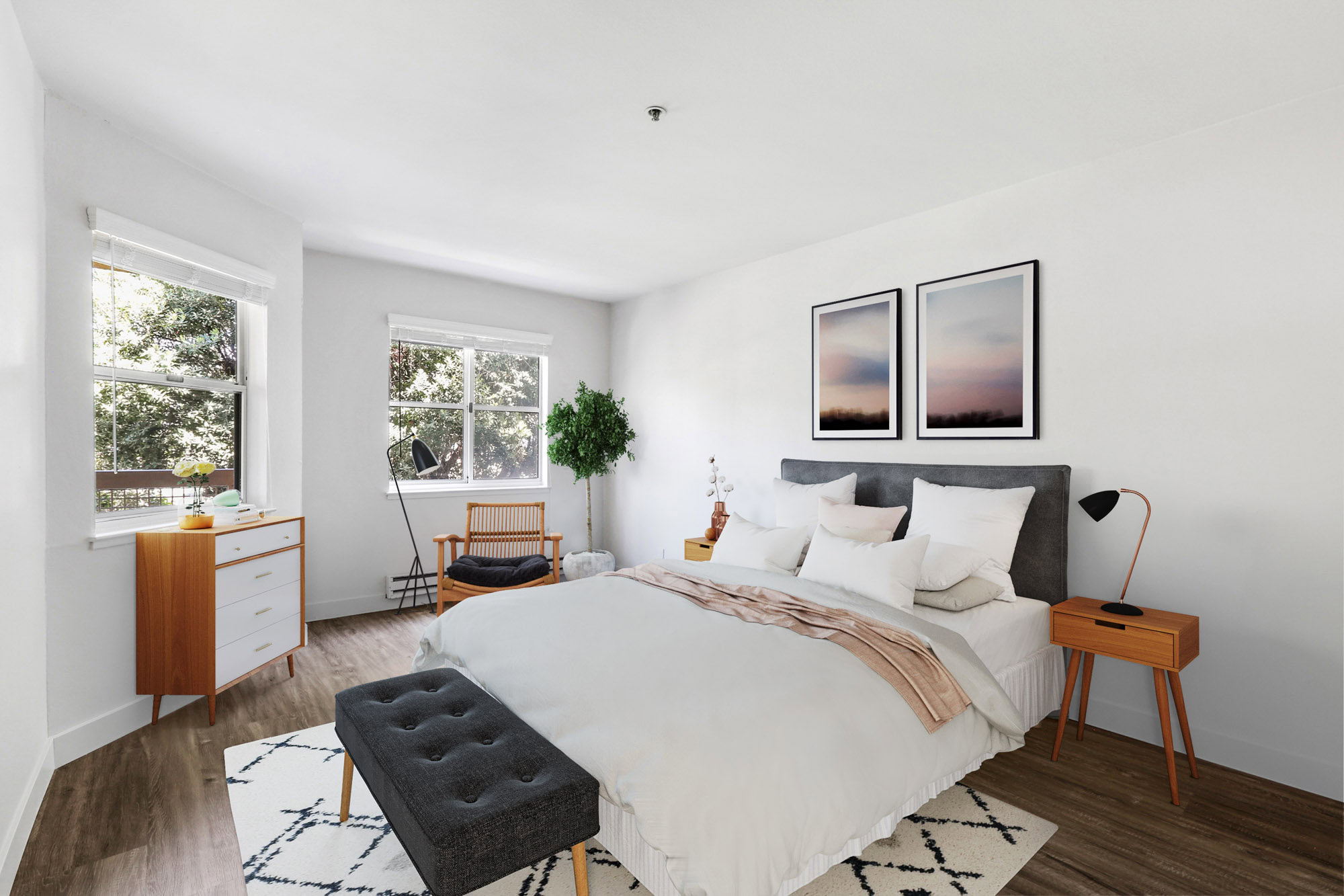A bedroom with hardwood floors and two windows at Bayside Village apartments in downtown San Francisco