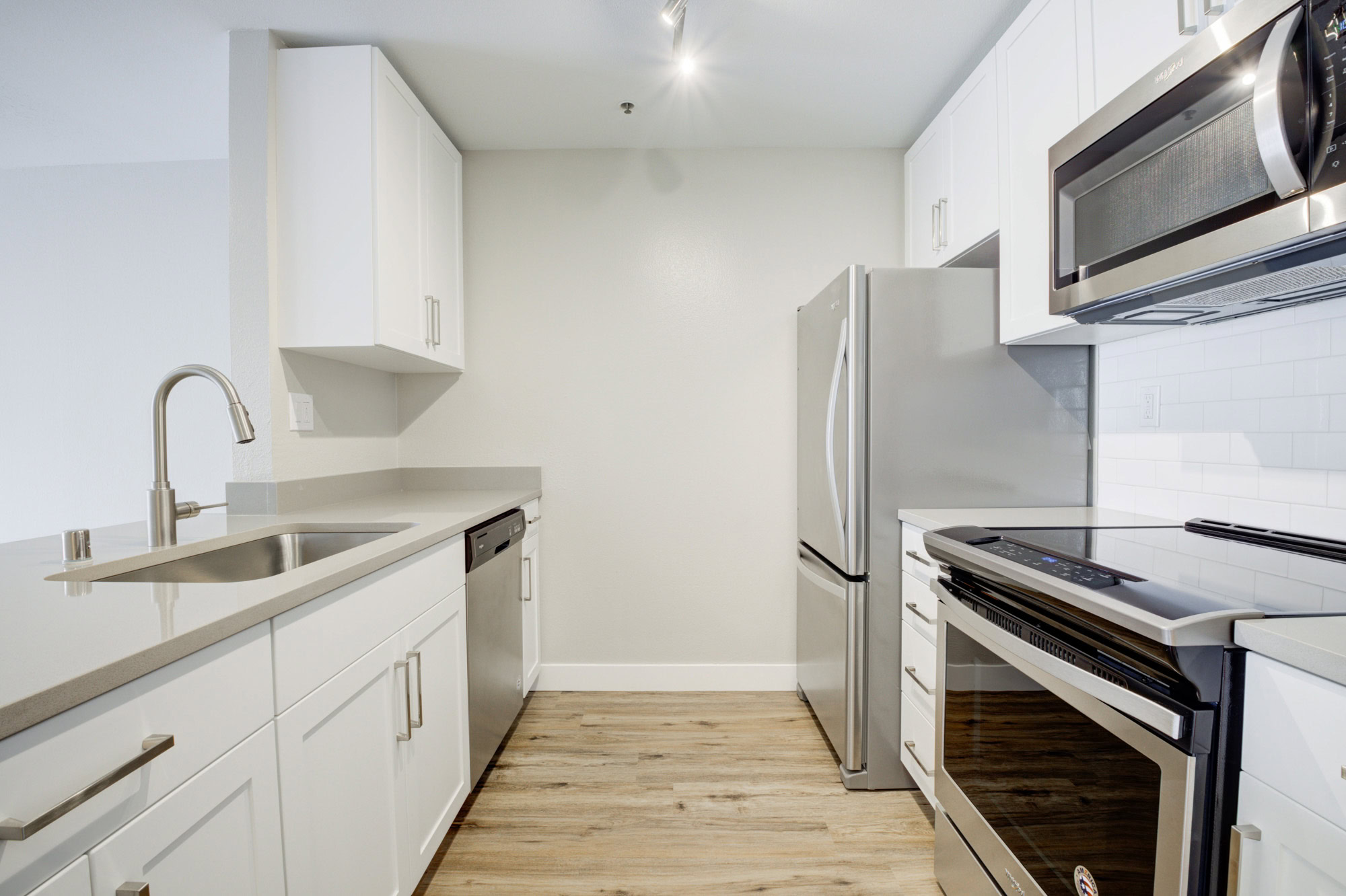 A double galley style kitchen with white cabinets and stainless steel appliances in a Bayside Village apartment in San Francisco