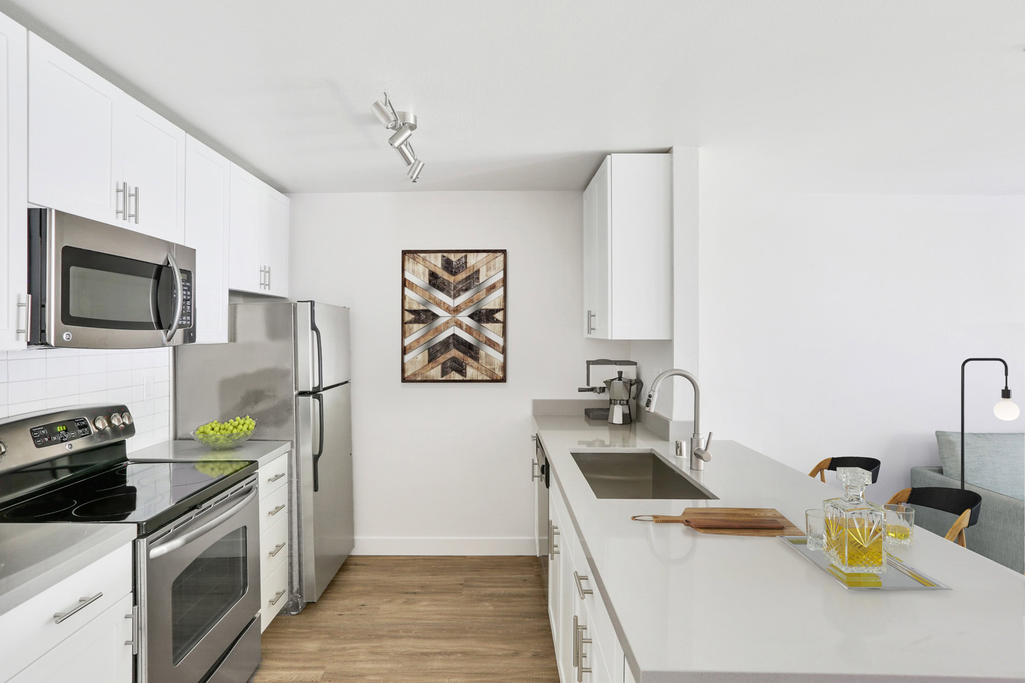 A double galley style kitchen with white cabinets and stainless steel appliances in a Bayside Village apartment in San Francisco