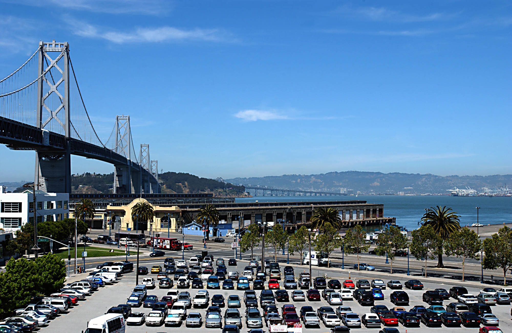 A parking lot near the coast of the city, with the Bay Bridge in the nearby distance in a neighborhood near Bayside Village in San Francisco