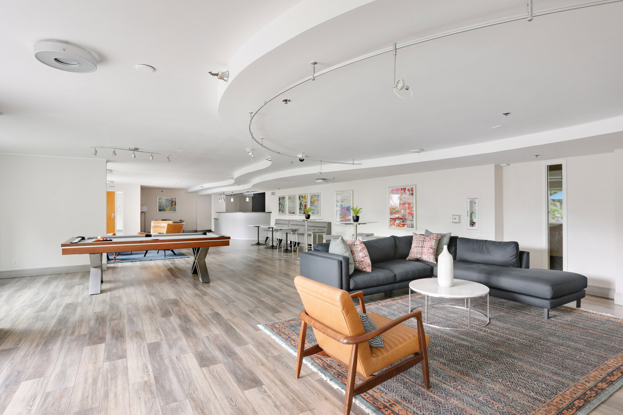 A spacious lounge with a couch seating, a pool table and dining space at The Met apartments in downtown Los Angeles