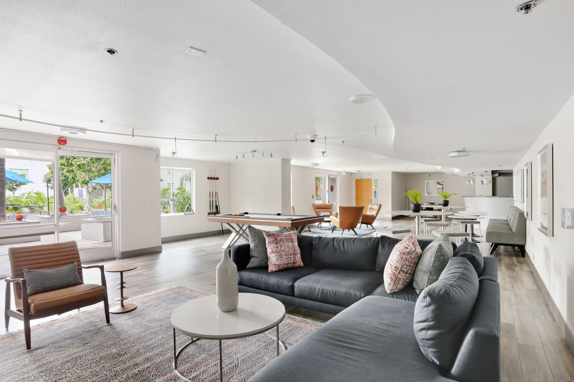 A lounge L shaped couch, dining area and pool table in a spacious club room at The Met apartments in downtown Los Angeles