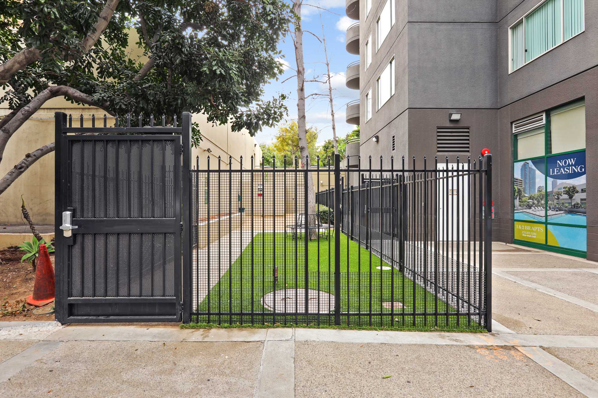 A gated dog run with faux grass and a seating area at The Met apartments in downtown LA
