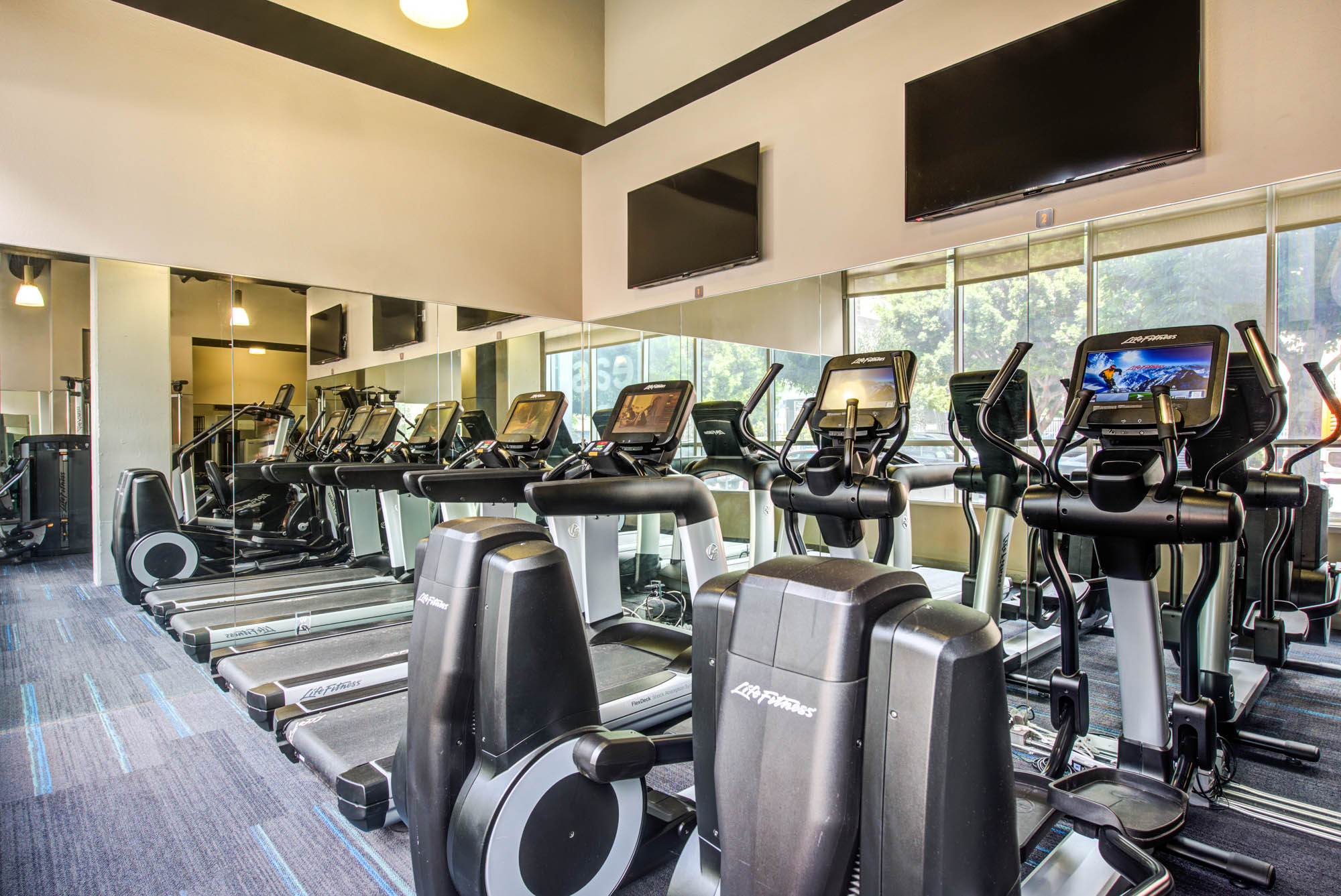 A fitness center with treadmills and other cardio machines lined up at The Met apartments in downtown LA