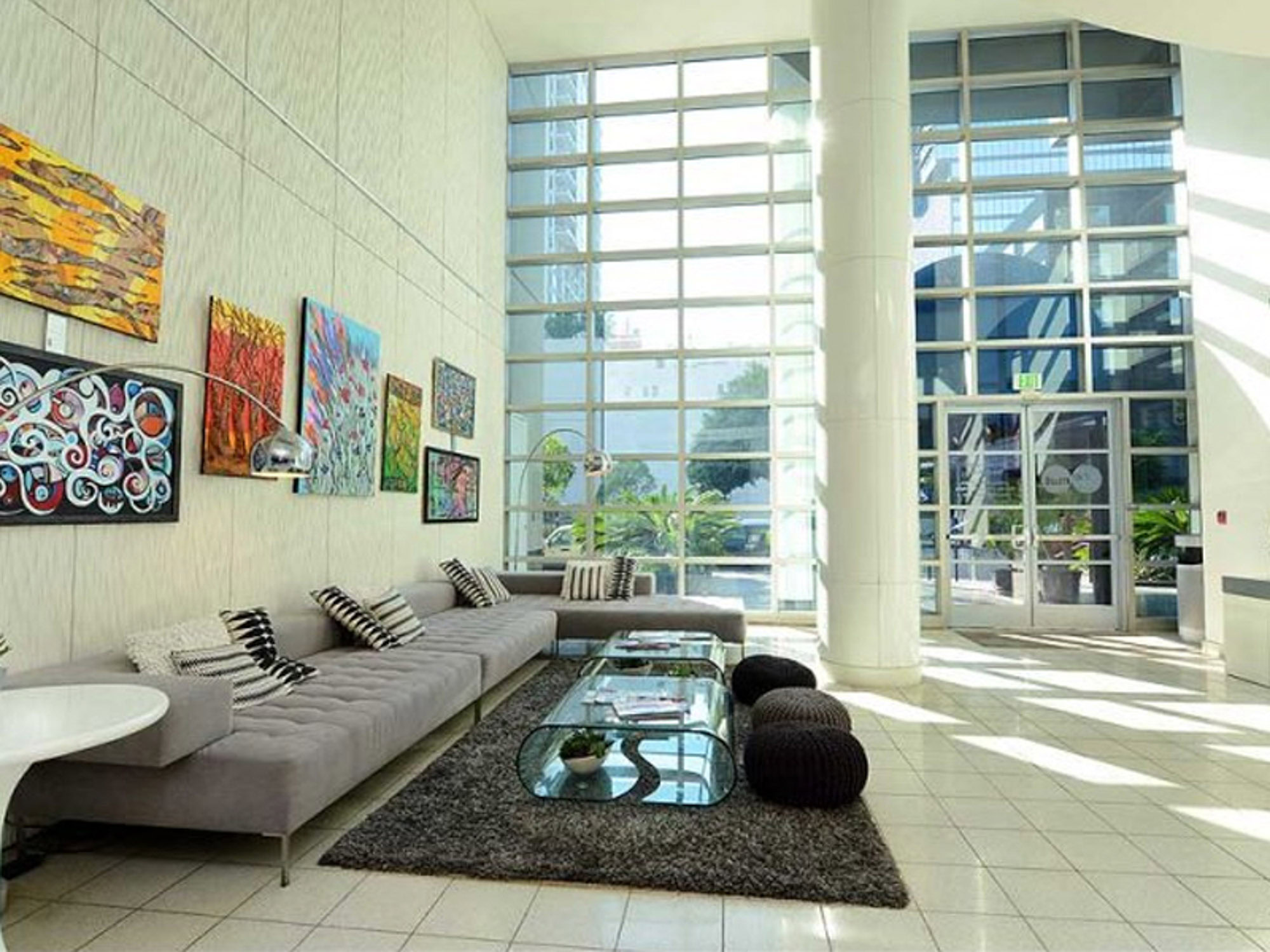 A modern lobby with a large floor to ceiling window wall, couches and wall art at The Met apartments in downtown Los Angeles California