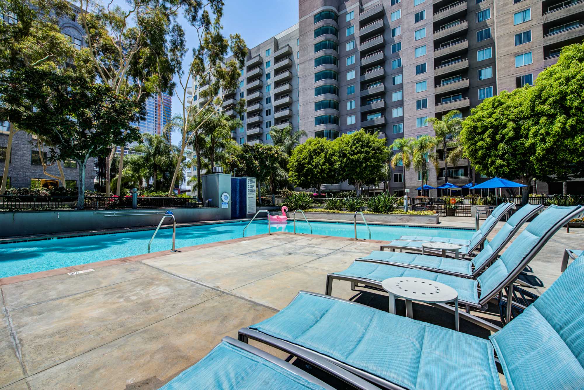 Blue lounging chairs next to a pool, surrounded by apartments at The Met in downtown LA