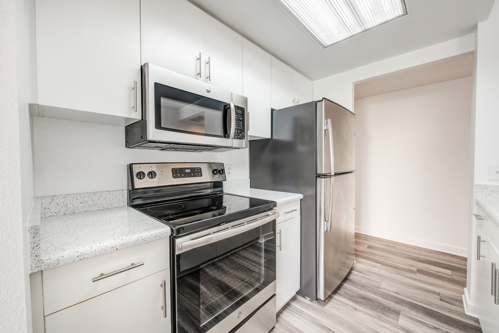 A kitchen with hardwood floors and white cabinets at The Met apartments in downtown LA
