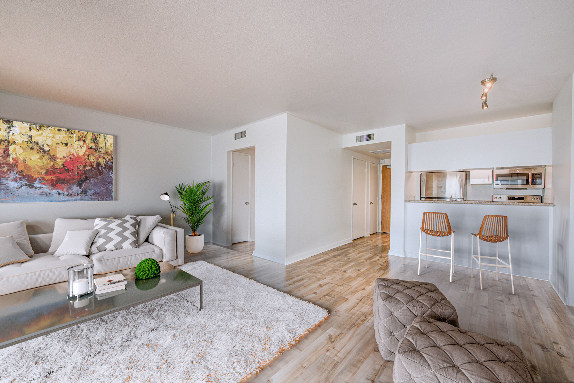 A living room with hardwood floors and kitchen counters facing the living room at The Met apartments in downtown LA
