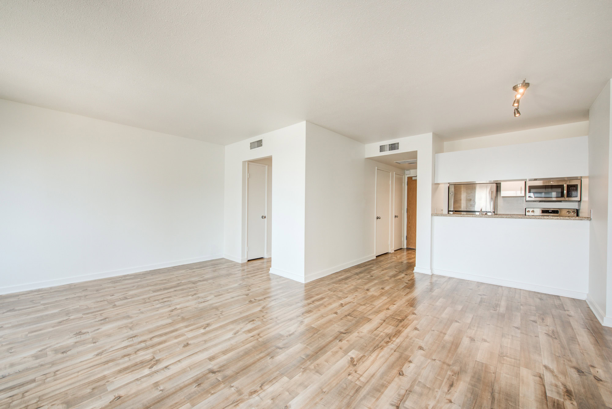 An empty living room with hard wood floors and a partition wall at The Met apartments in downtown LA