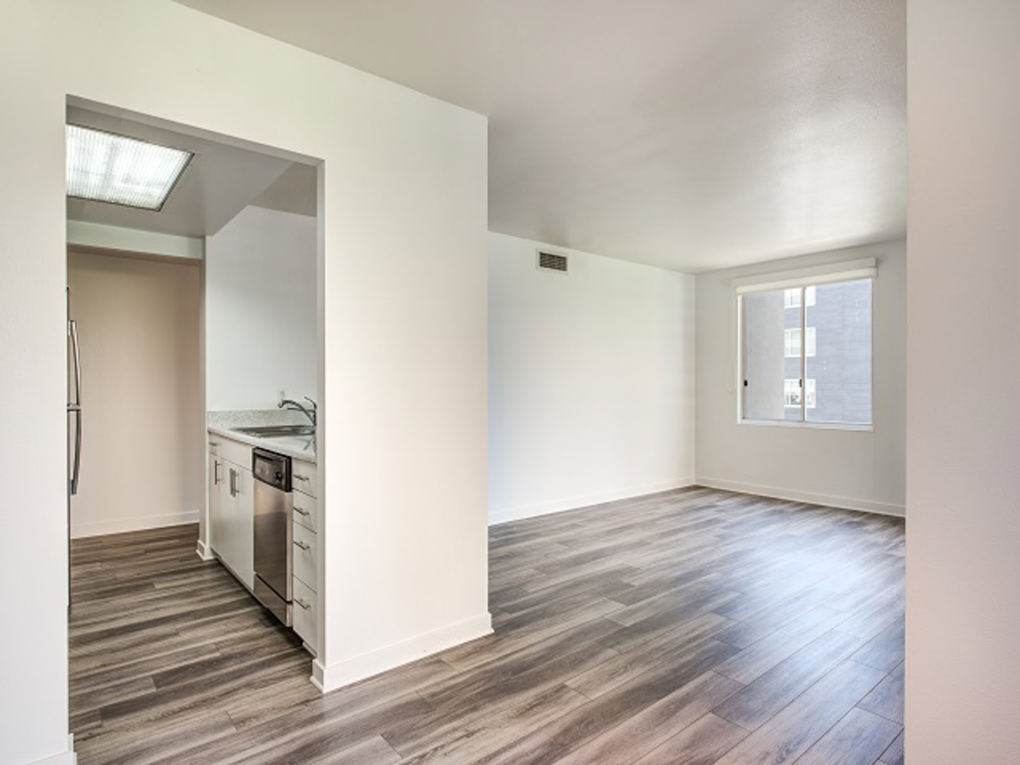 An empty kitchen a living room with hardwood floors and a window at The Met in downtown LA