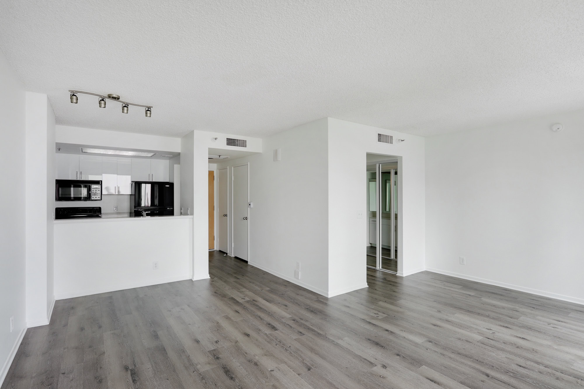An empty studio living room with a partition wall and a frame looking into the kitchen at The Met modern apartments in downtown LA