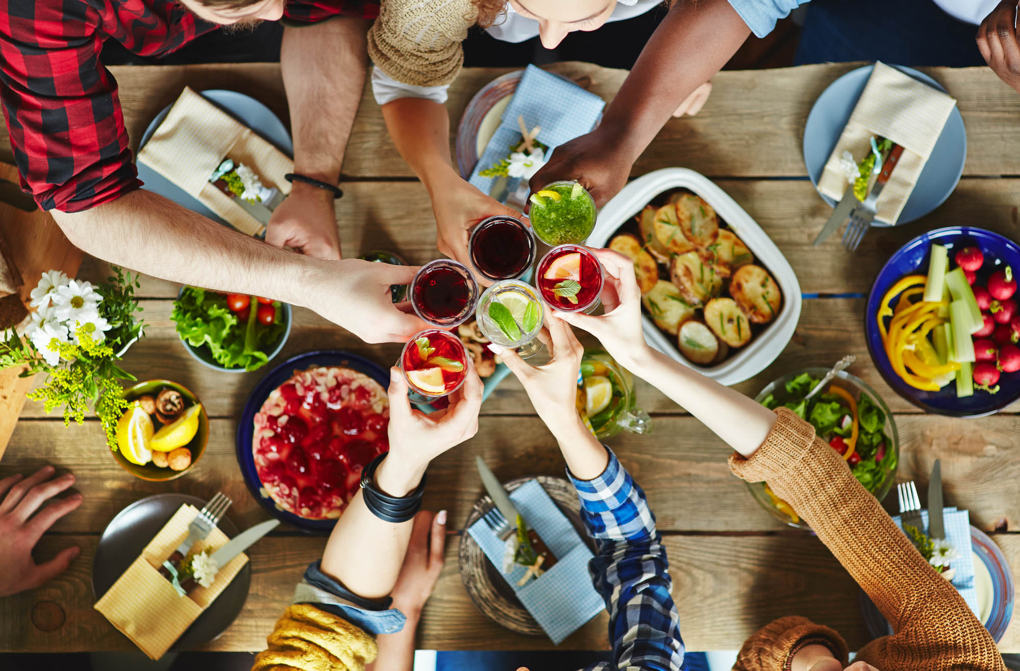 An aerial shot of a group of people cheersing their drinks over a table full of food in the South Park neighborhood in DTLA