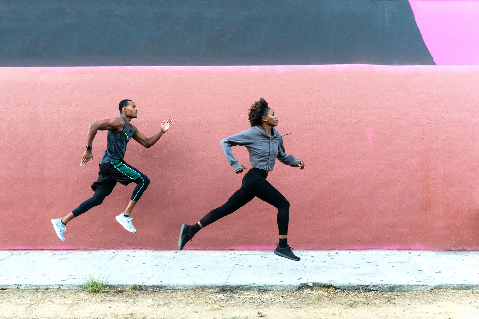 Two people running by a pink wall in the South Park neighborhood near The Met apartments in downtown LA
