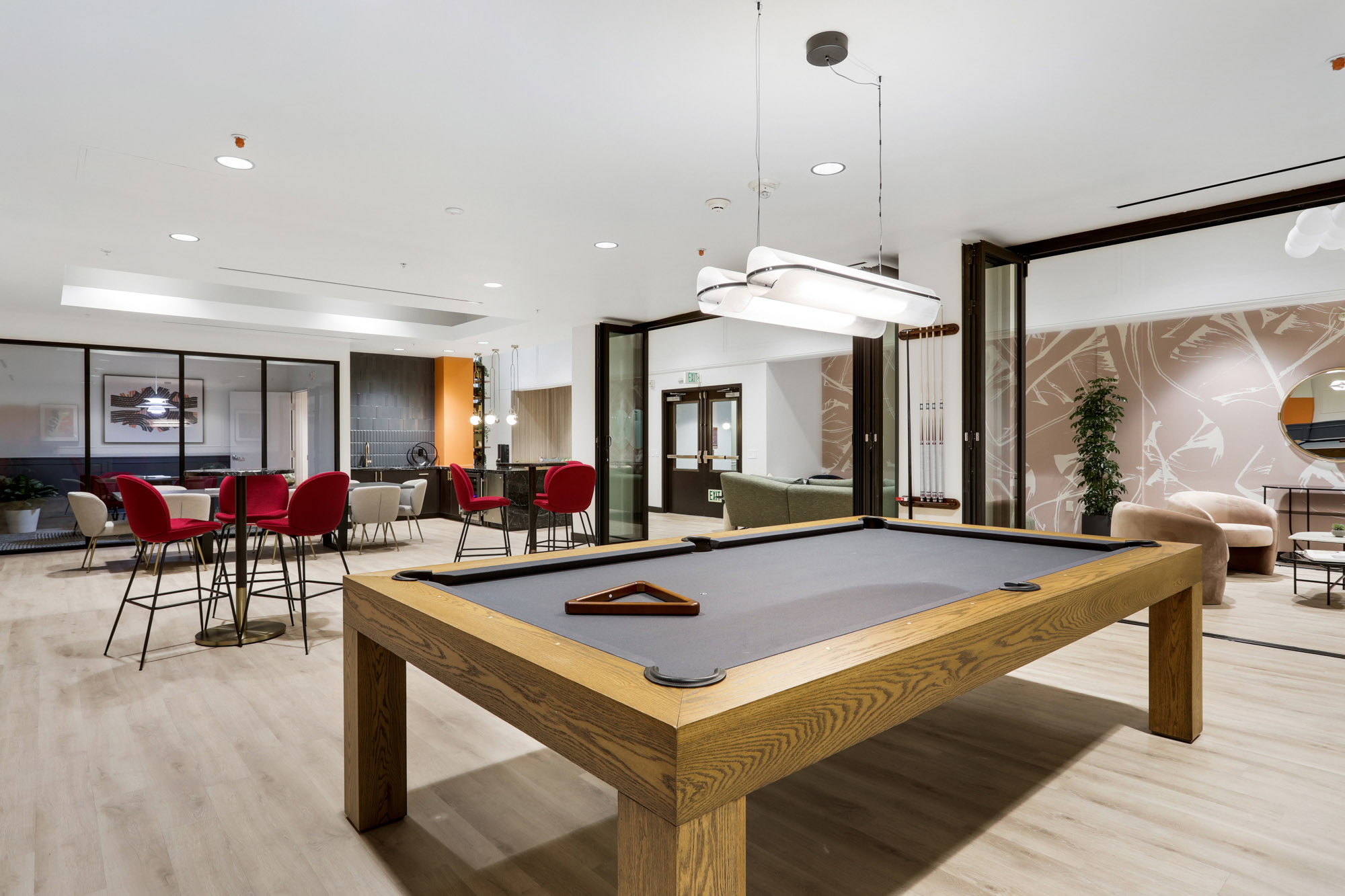 A game lounge with a pool table, high tables and chairs, and private rooms for entertaining and work at Metro 417's modern apartments in downtown LA