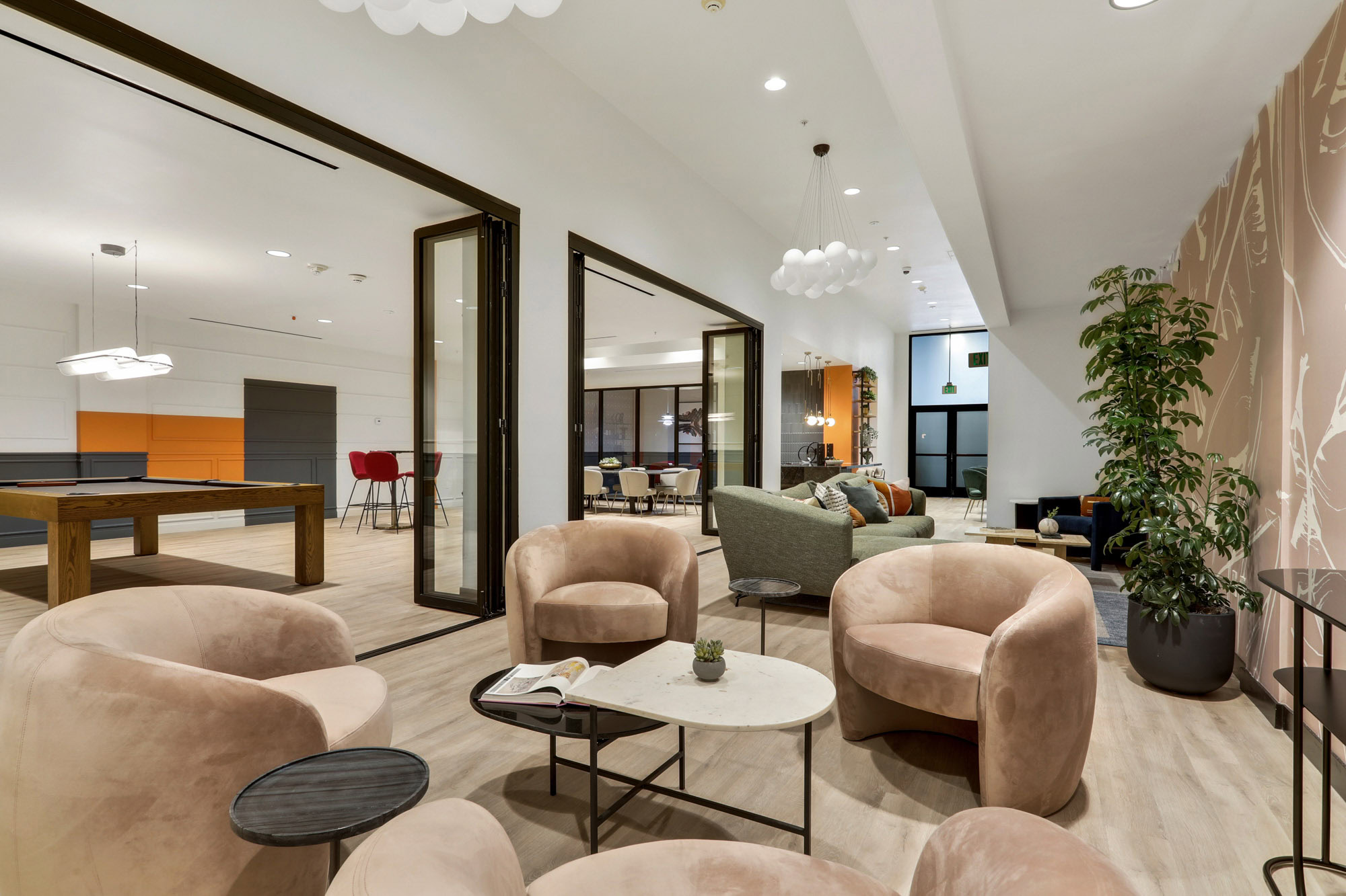 A game lounge private room seating area with open glass doors at Metro 417's modern apartments in downtown LA