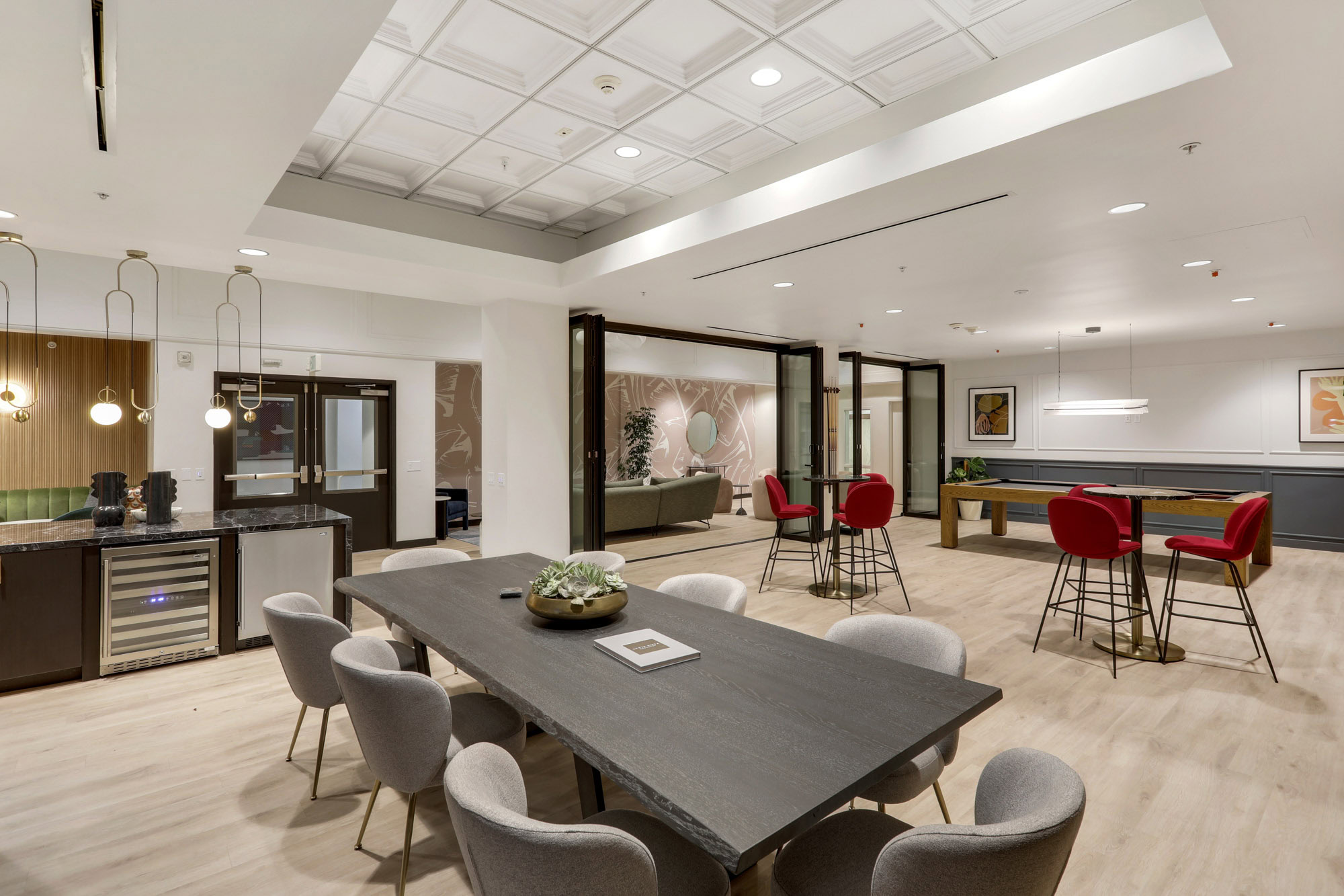 A game lounge with a dining table, kitchen area, high tables and pool tables at Metro 417's downtown LA apartments