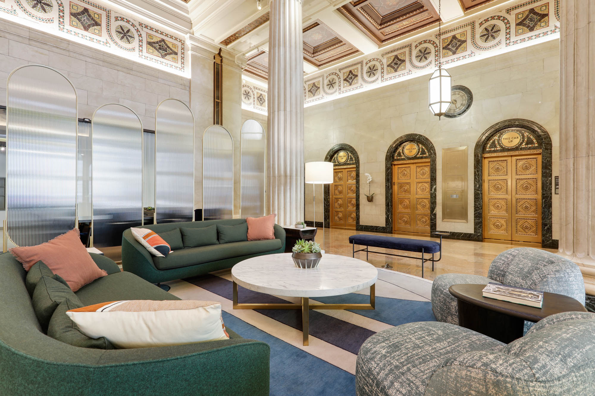 A Beaux arts themed lobby lounge in front of gold-trimmed vintage elevator doors at Metro 417's apartments in DTLA