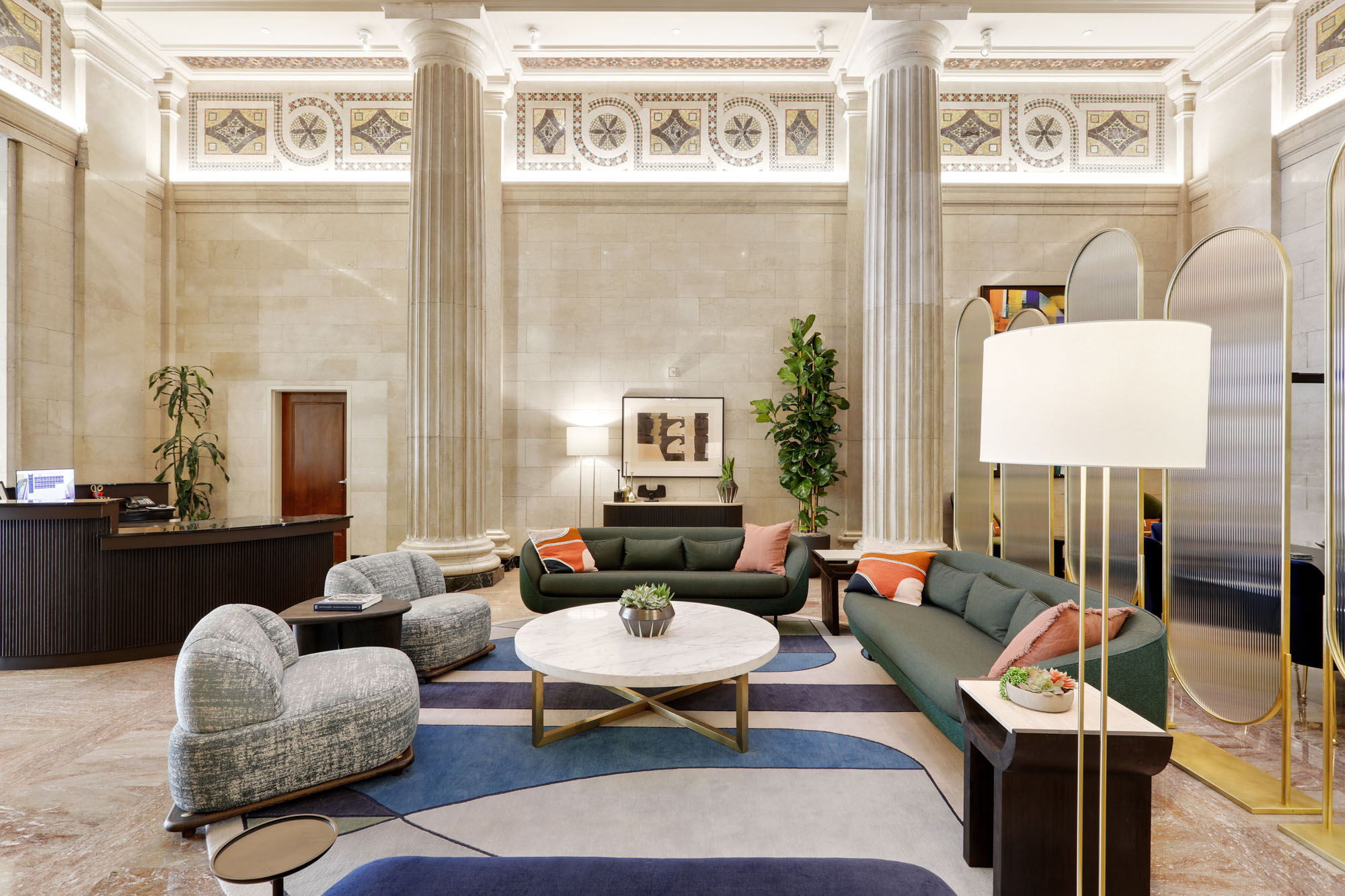 A Beaux arts themed lobby lounge in front of the front desk with arched glass panels at Metro 417's modern apartments in DTLA