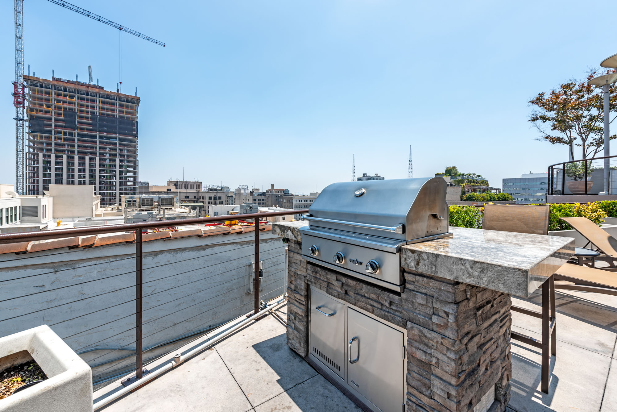 An outdoor grill on the roof with the pool with city views at Metro 417 apartments in downtown LA
