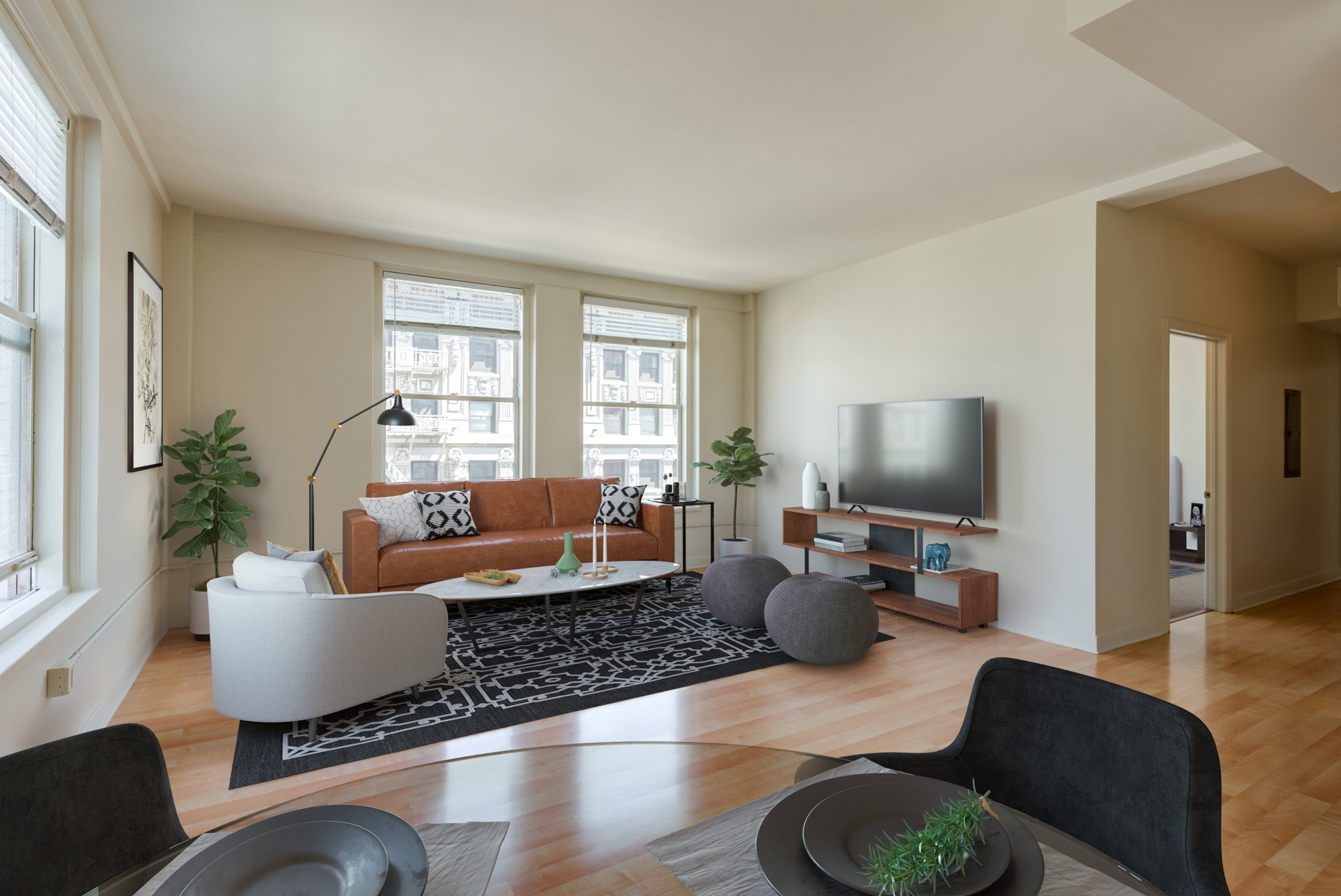 An open plan living room and dining area with three windows and a halway to the bedrooms at Metro 417's modern apartments in DTLA
