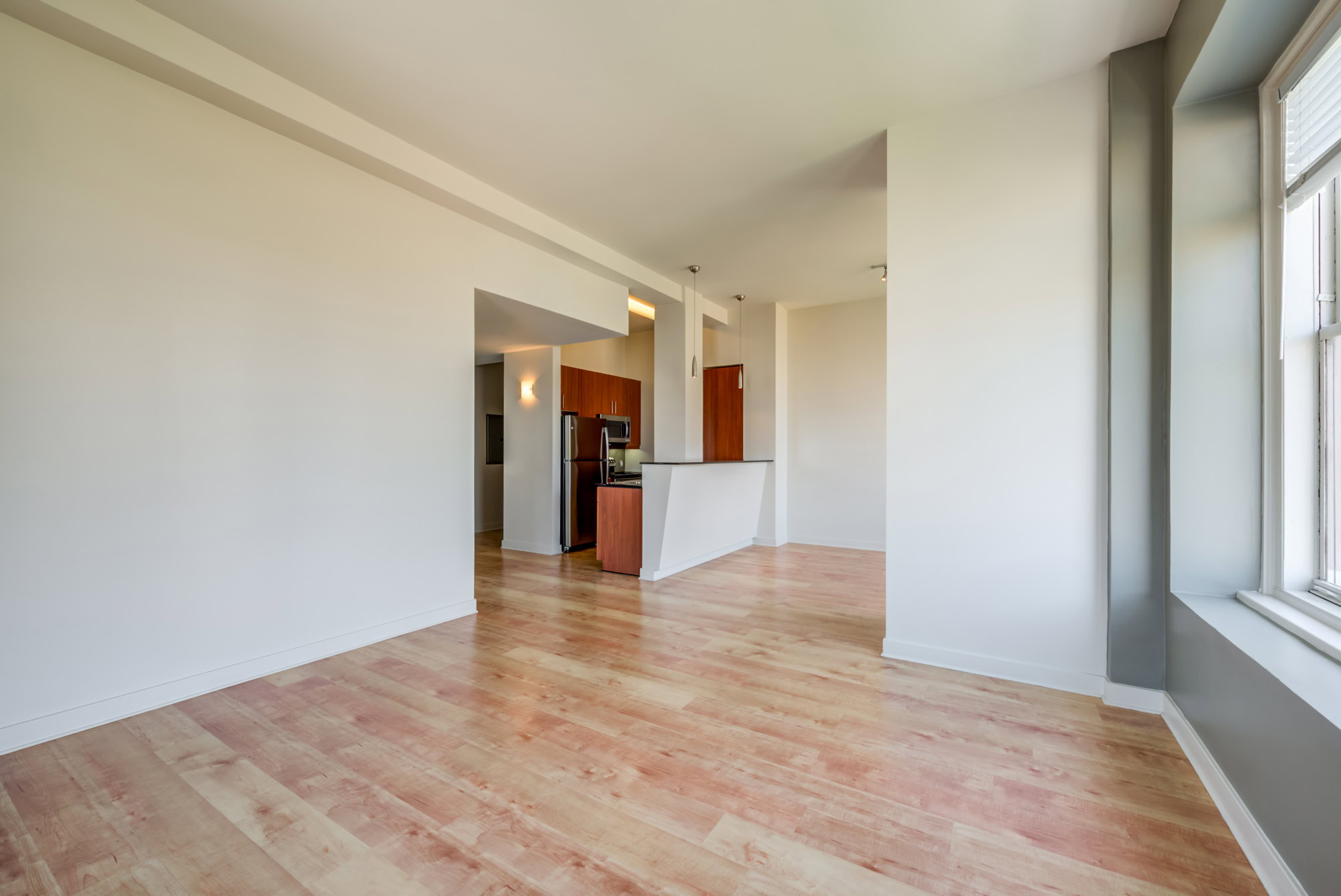 A living room with windows, with a kitchen compact U-shaped kitchen at Metro 417 apartments in downtown LA