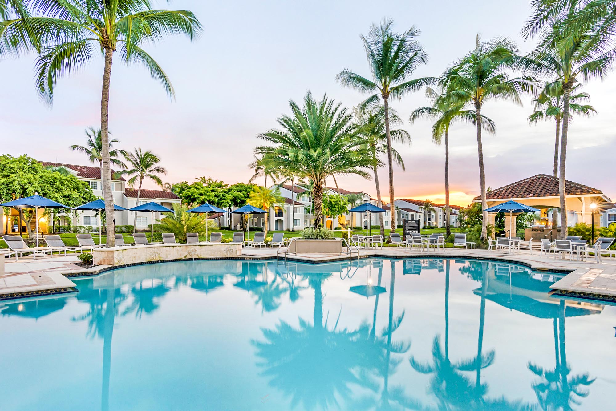 A pool surrounded by lounging chairs at Miramars luxury apartments for rent