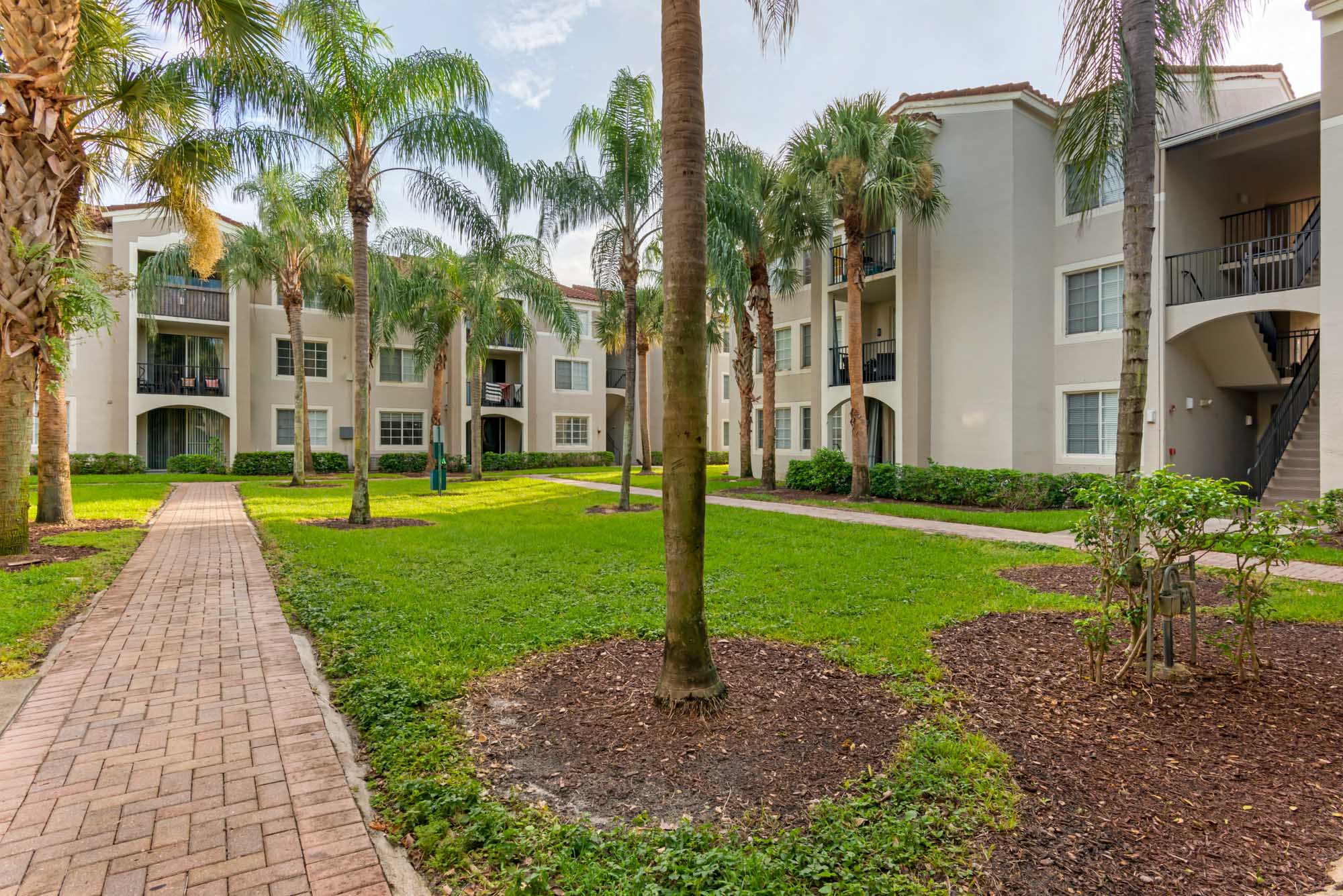 The courtyard with a walk path at Miramar Lake apartments in Fort Lauderdale, FL.