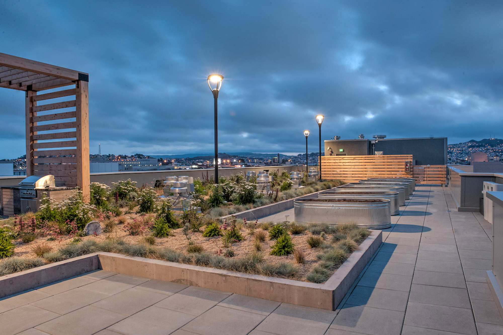 A rooftop terrace with desert plants, lights and cabana's, giving city views from Mosso apartments in San Francisco